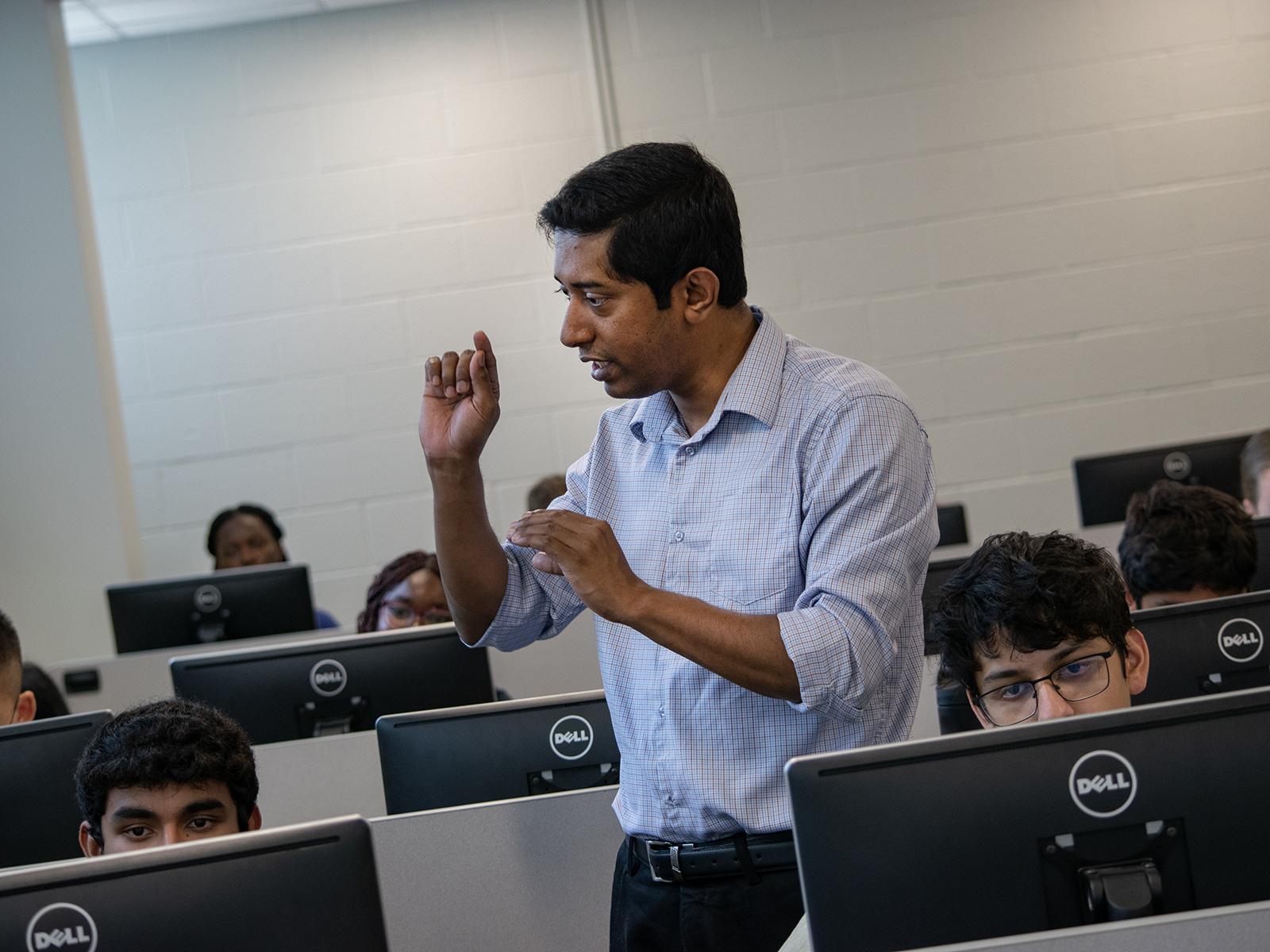 A professor instructs students sitting at computers