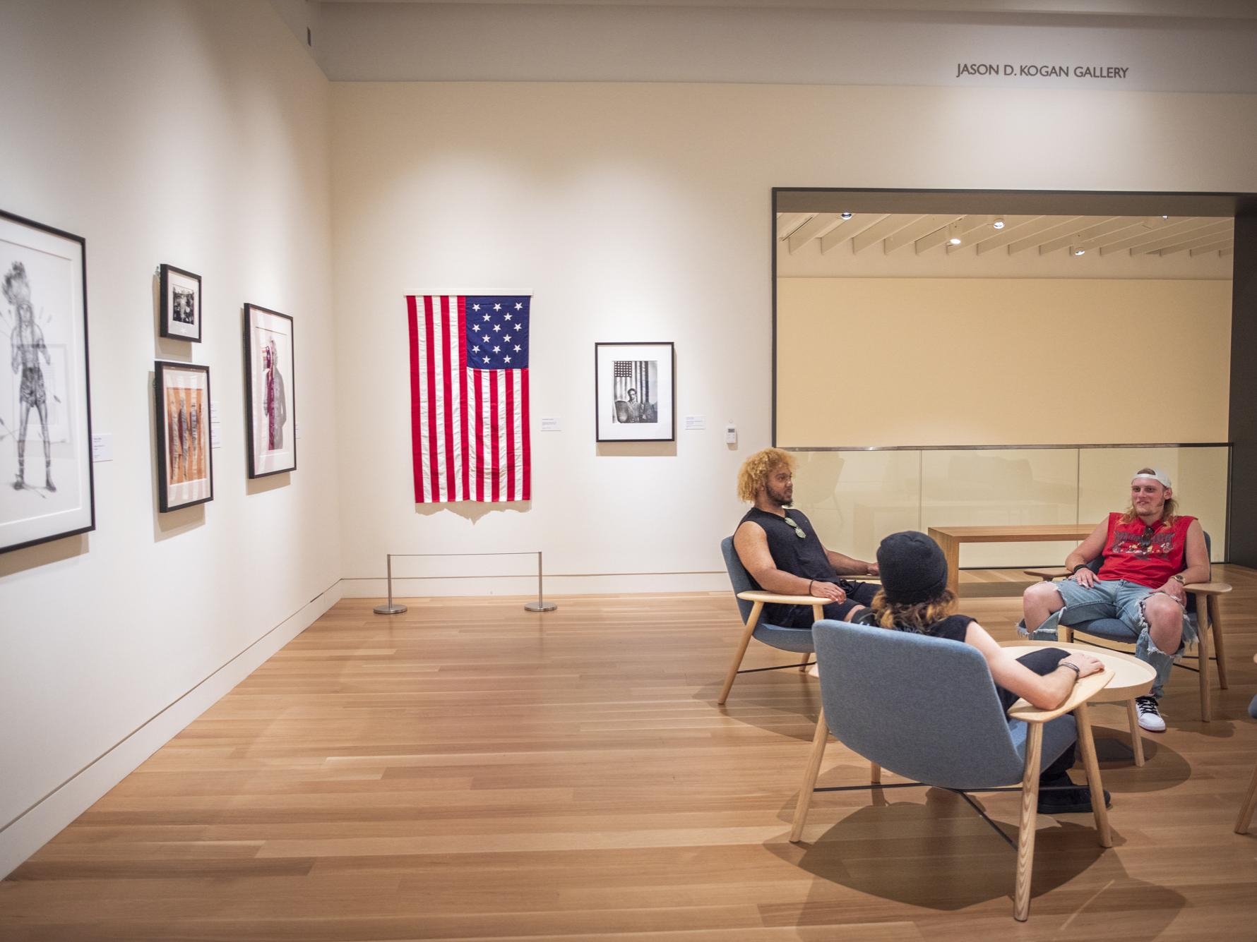 Three people sitting on chairs in an art gallery
