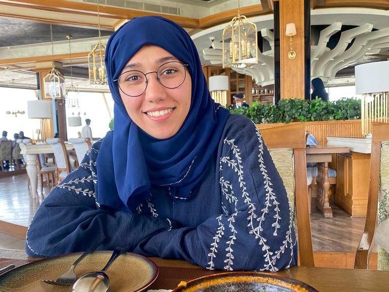 Fatmah Almeer sits in a chair in a restaurant.