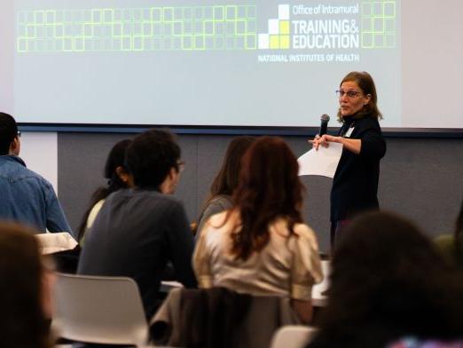 A woman stands in front of students in the front of a class room