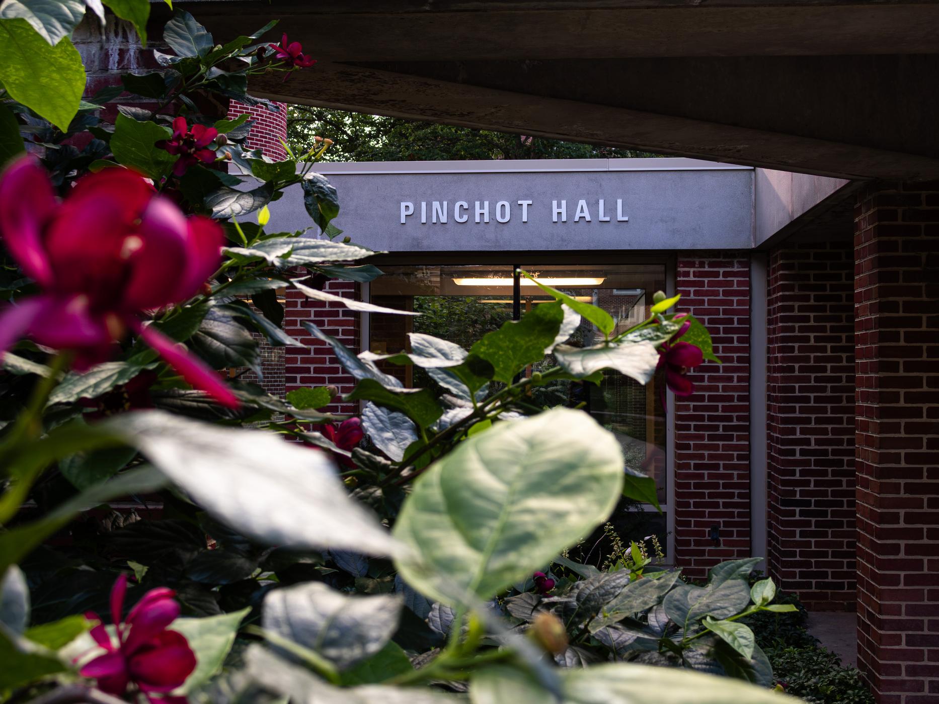 Red flowers in front of a building with a sign that reads "Pinchot Hall"