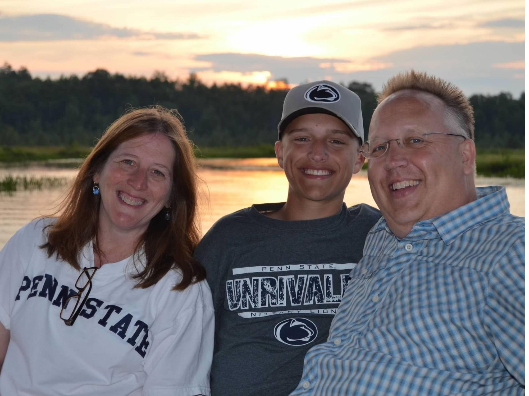 family of three on lake at sunset