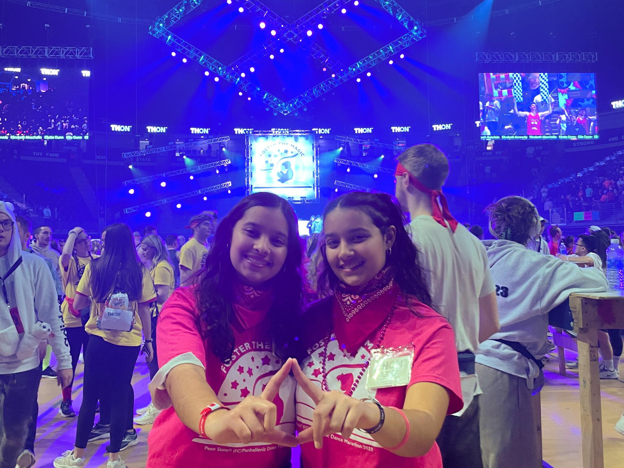 Olivia (left) and Abby Kayani at THON 2023 with their hands in the shape of a diamond.