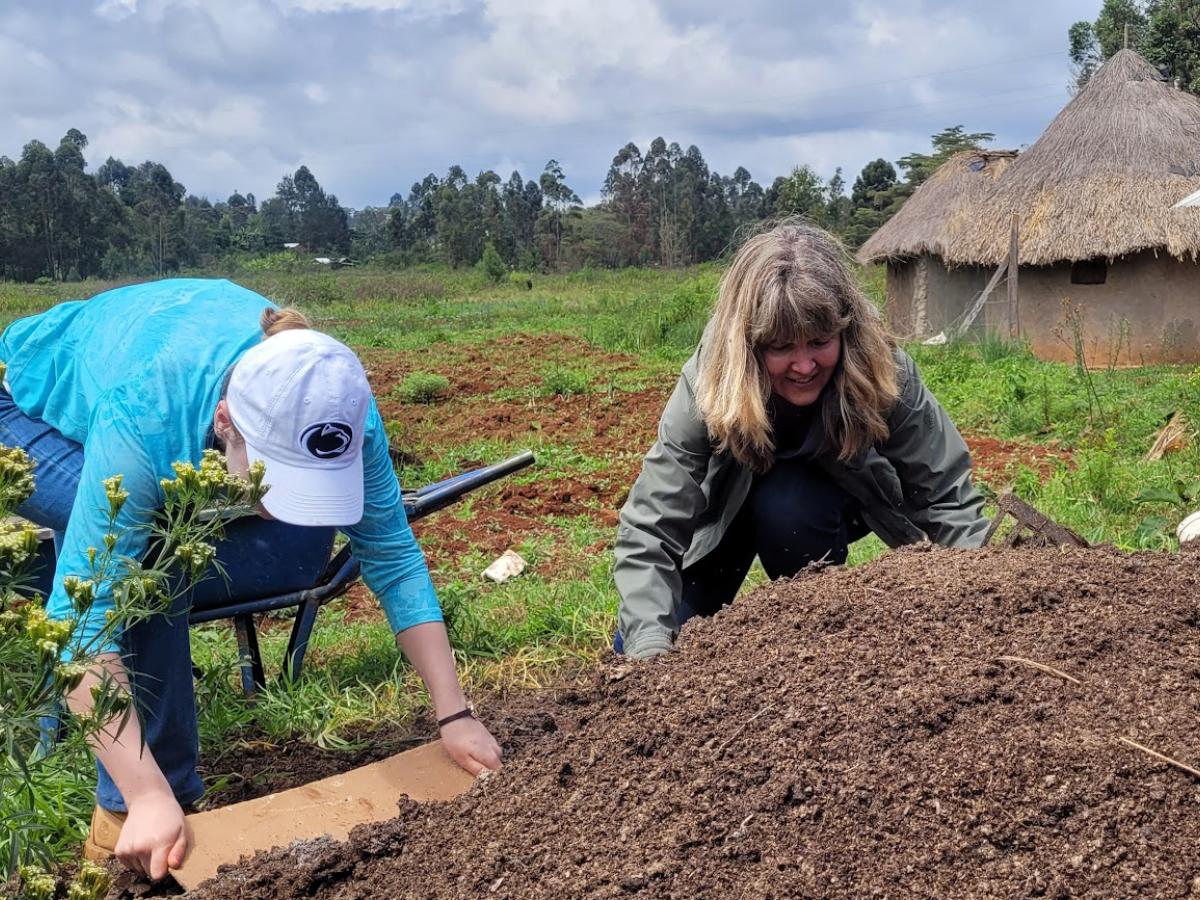 Janelle Larson and a student move manure in a pile