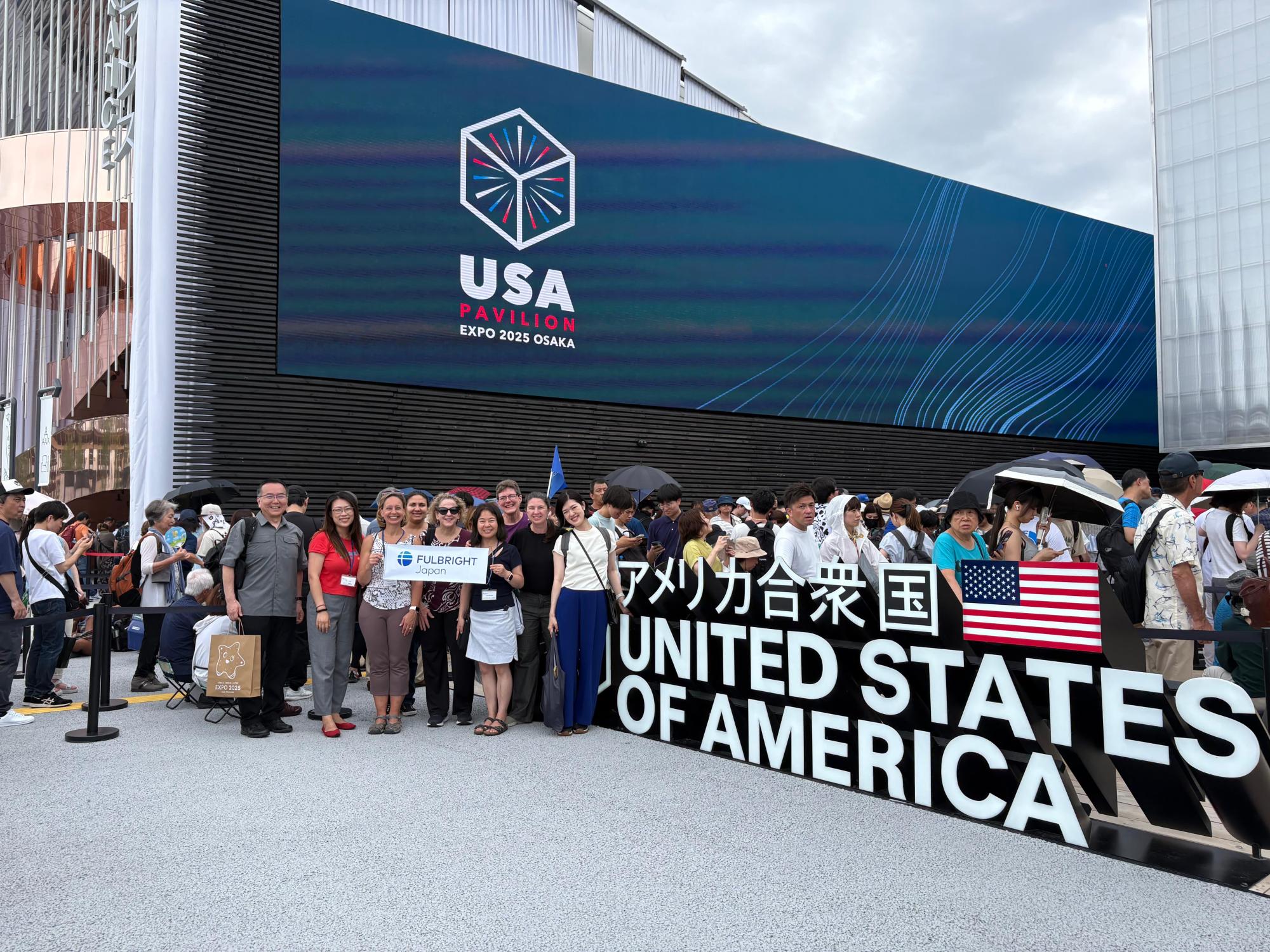 A group of seven people in front of a banner that says "United States of America"