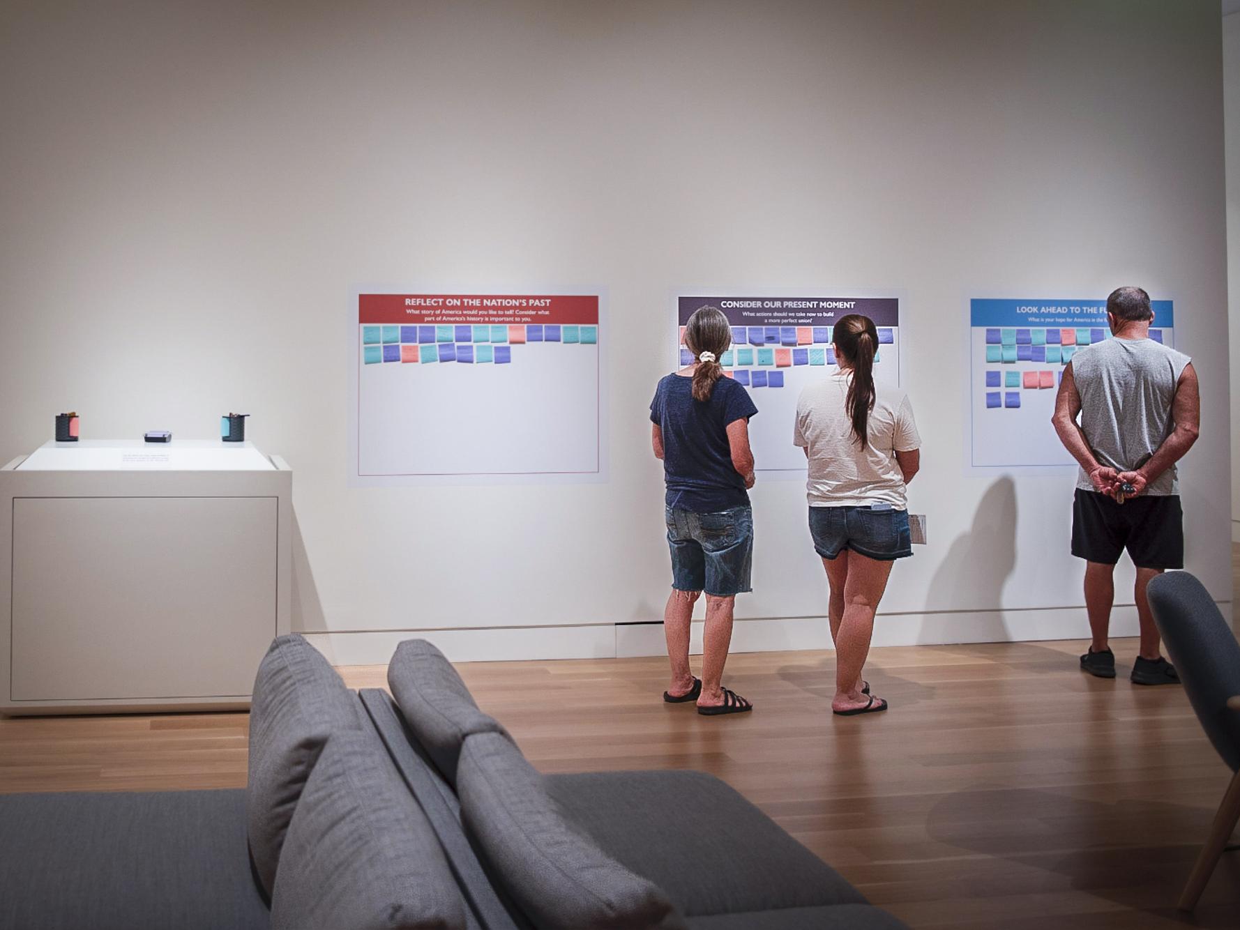 Three people in front of a wall with post-it responses