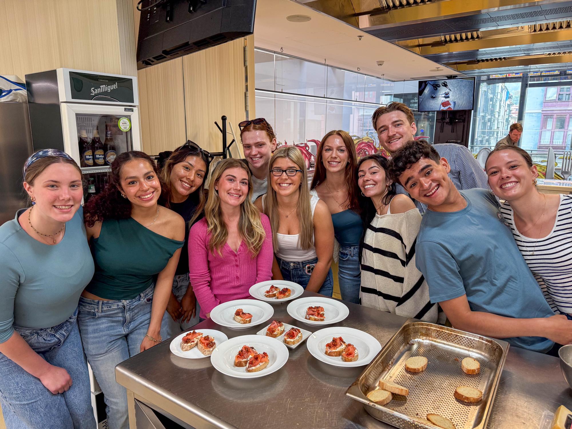 Penn State students stand around a food prep table with plates of pintxos while in Italy.