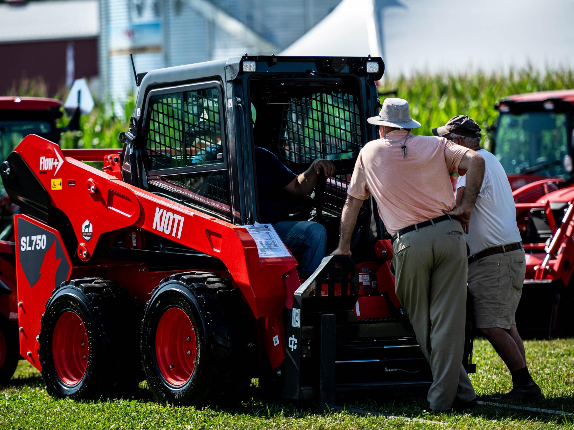 People looking and sitting on skid loader