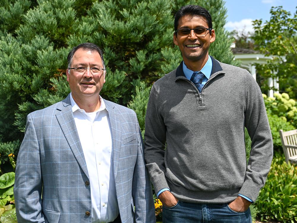 Two researchers standing outside in the sun taking a photo together
