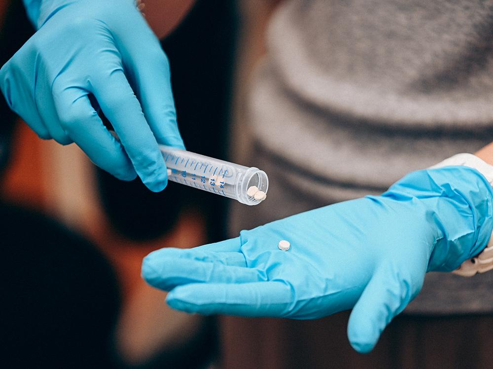 A lab worker spills out tiny scaffolds onto a gloved hand. 