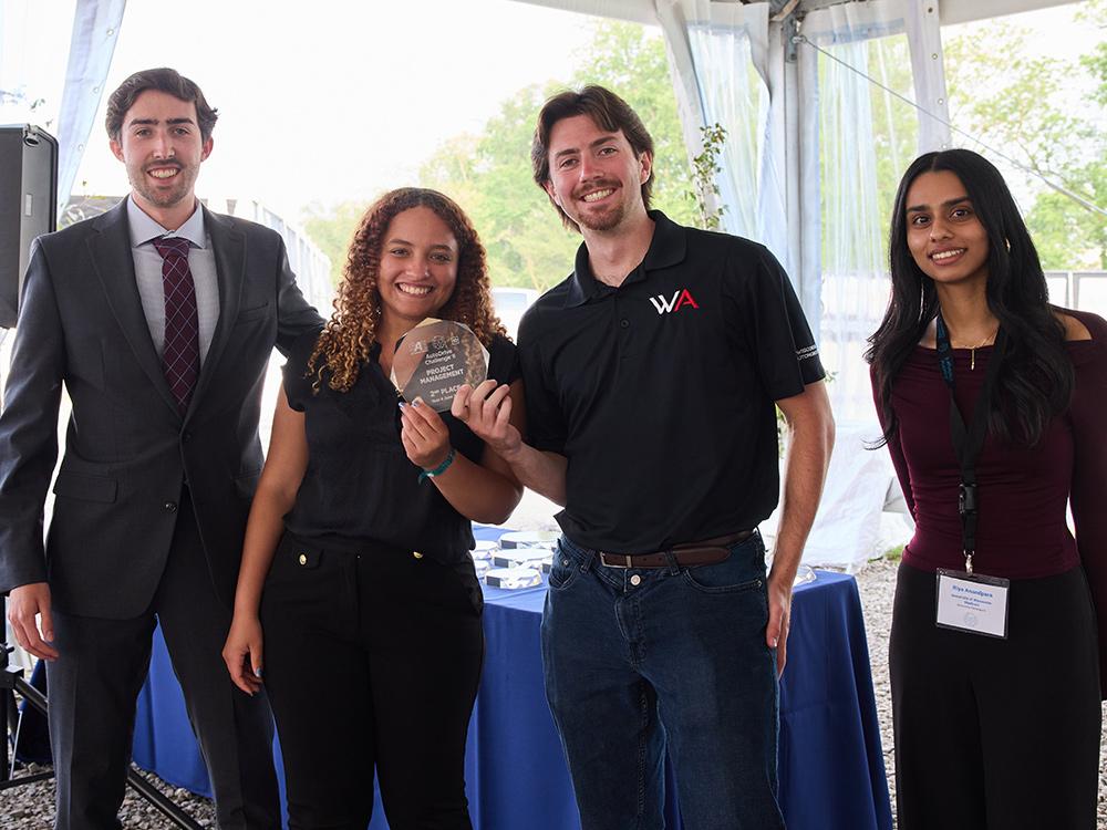 A group photo of four individuals holding a small plaque.
