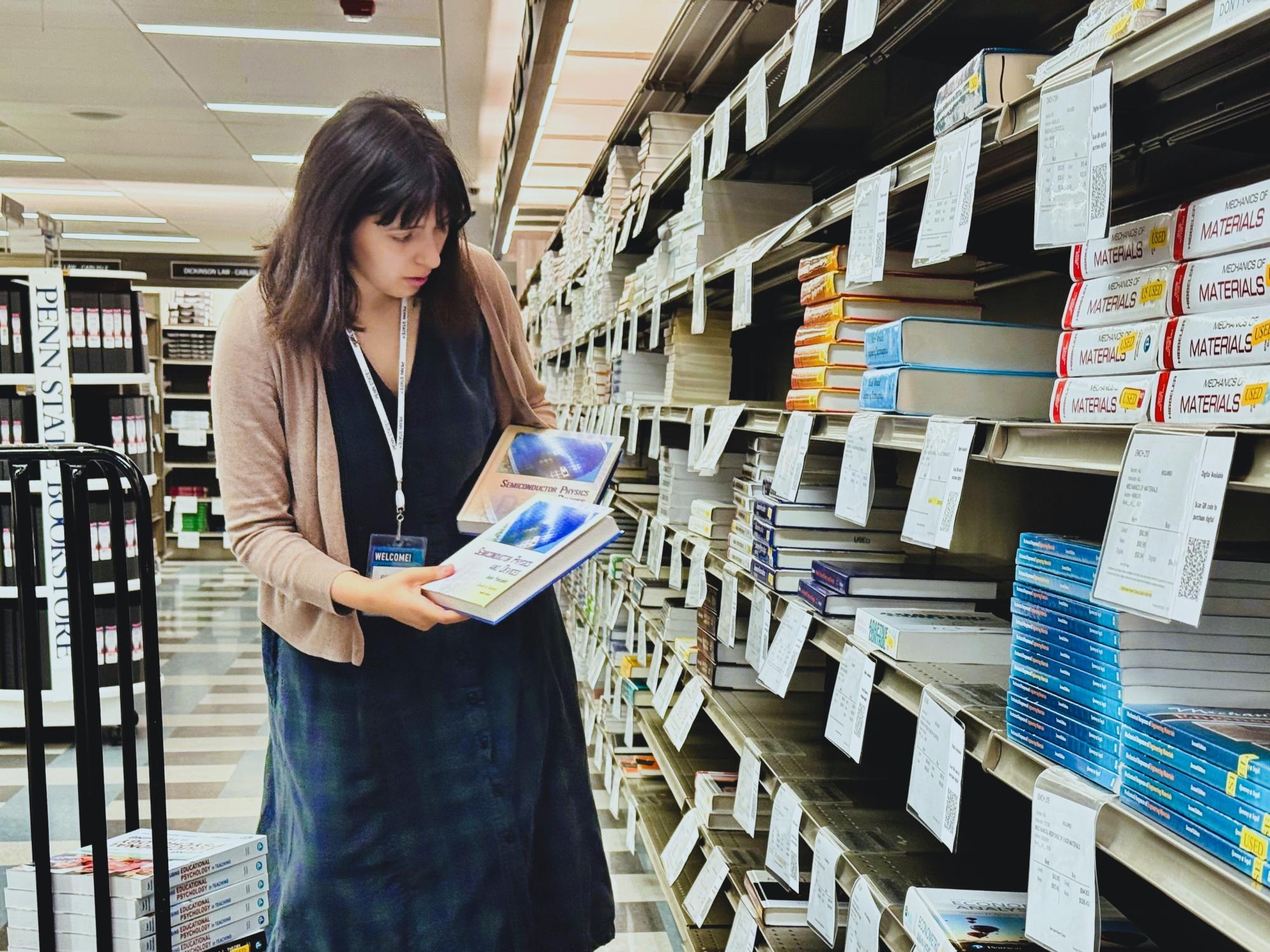 A staff member stocks textbooks on a shelf in a bookstore