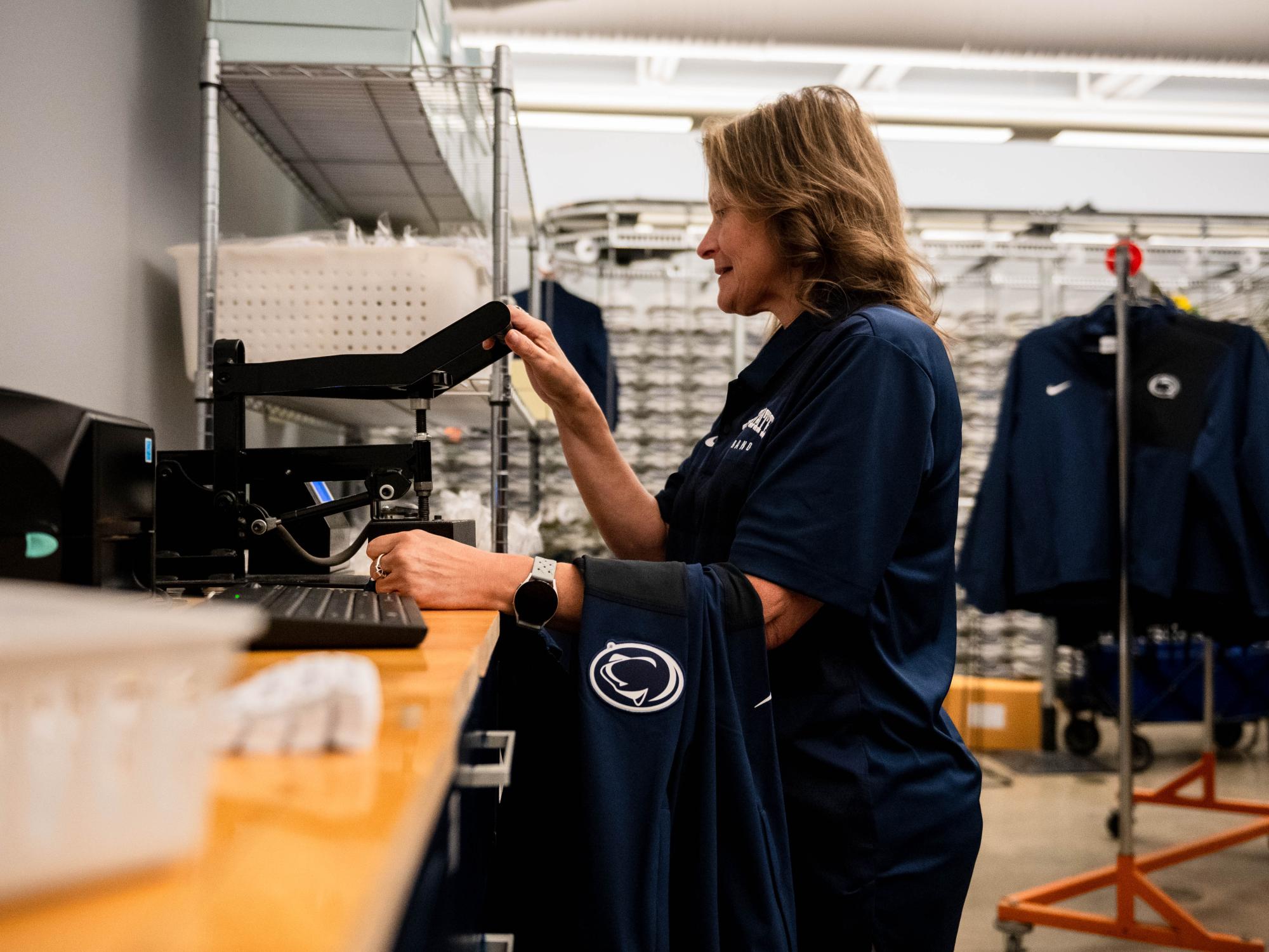 A woman operates a machine to press a barcode onto a piece of clothing
