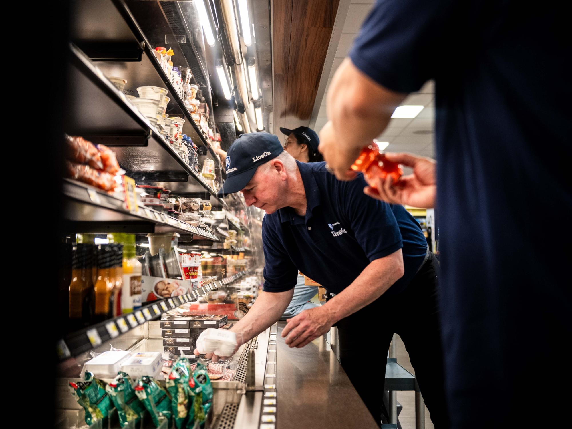 A staff member stocks a refrigerated aisle 