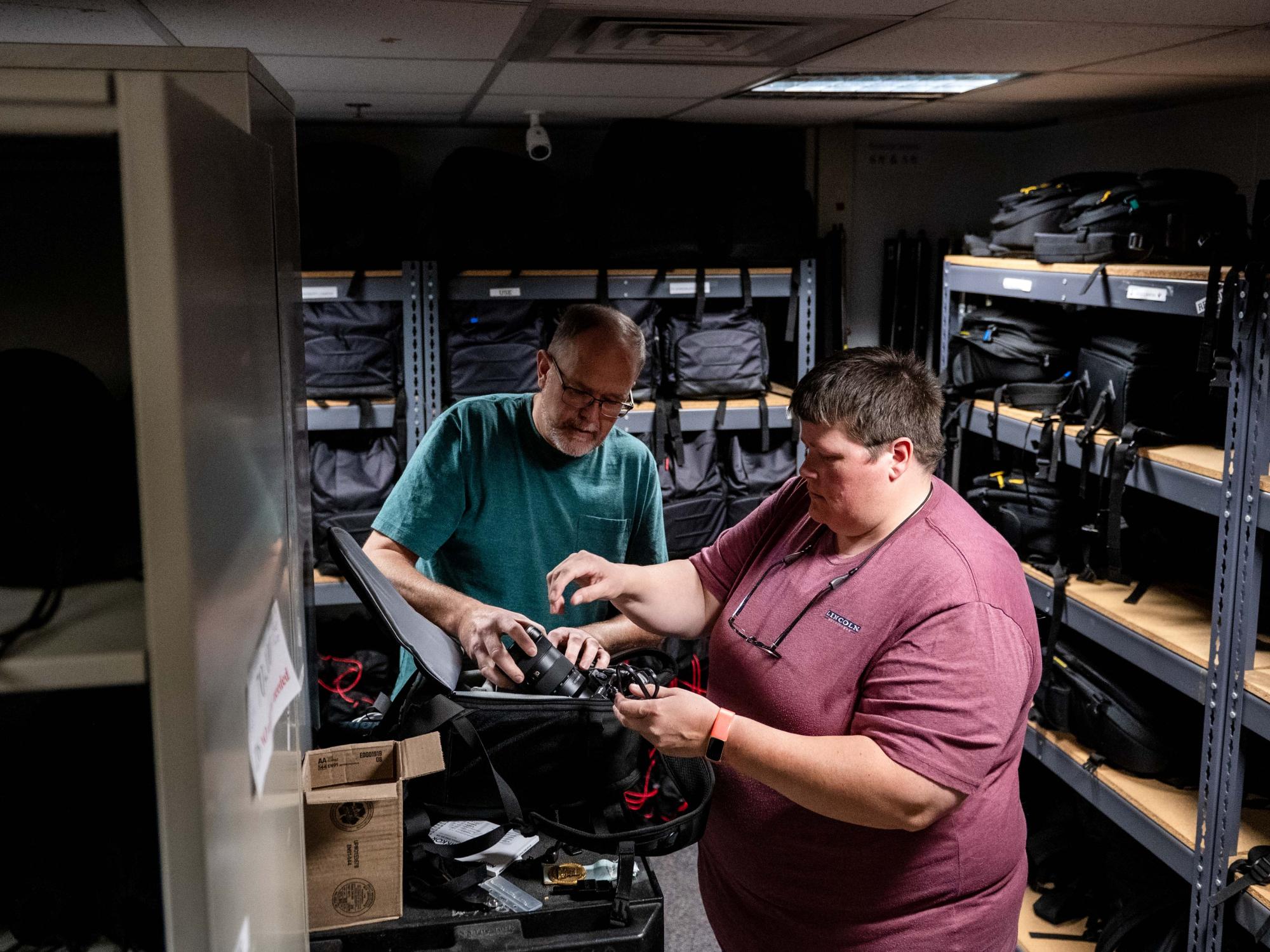 Two staff members inspect camera equipment