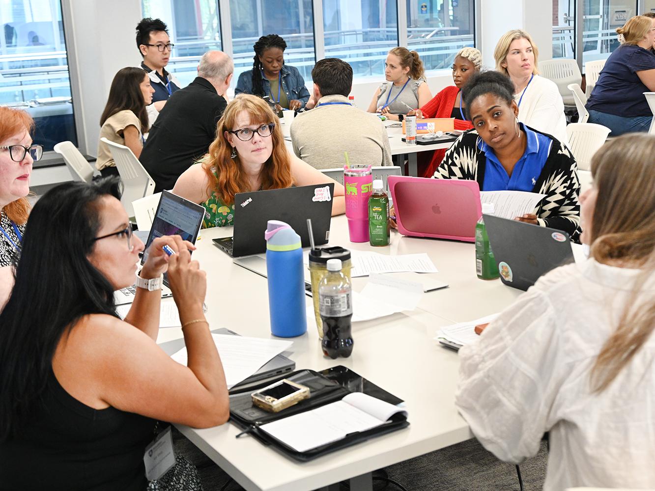 A group of students seated around a table holds a discussion during a small-group exercise