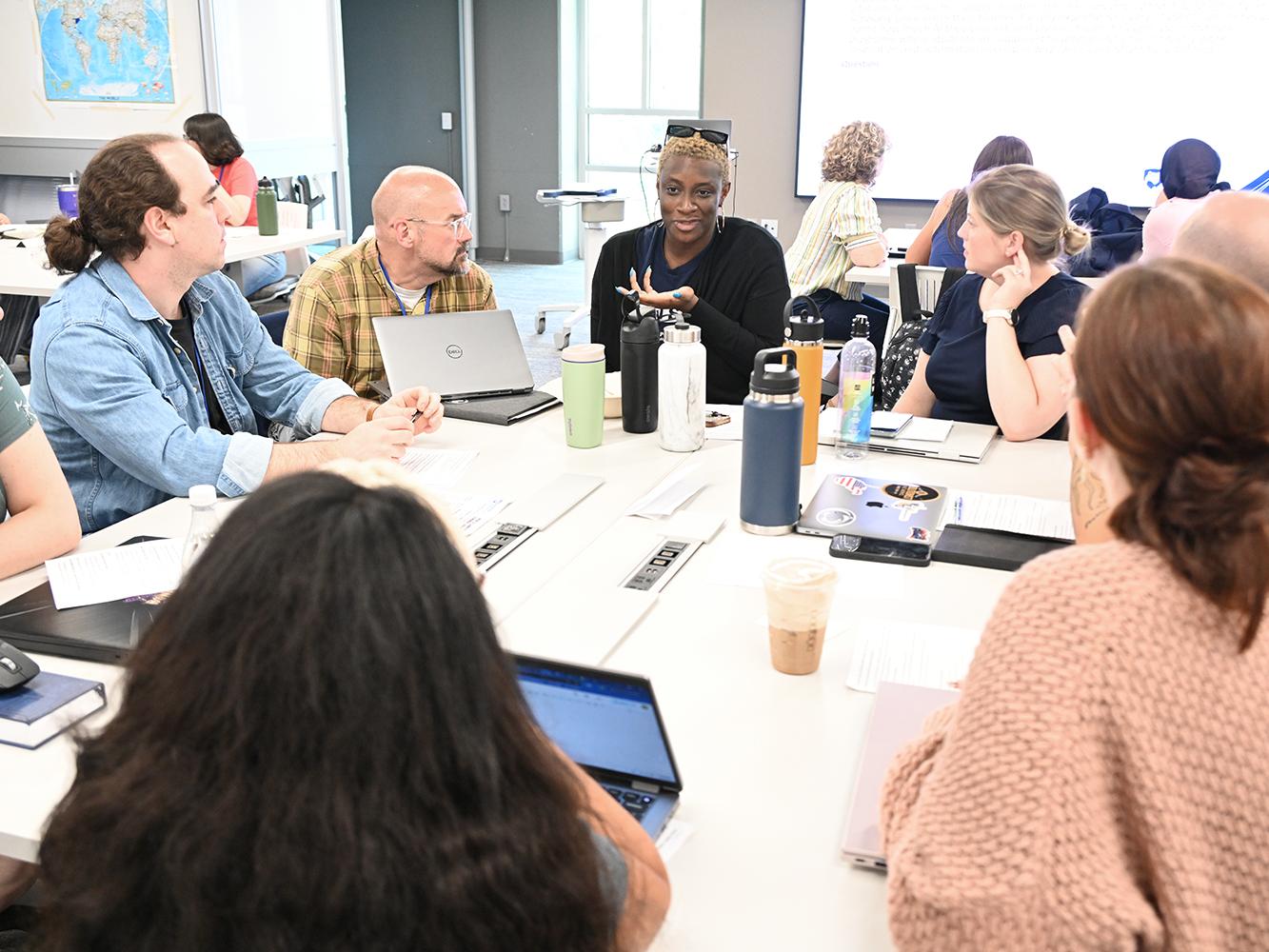 A group of students seated around a table holds a discussion during a small-group exercise.