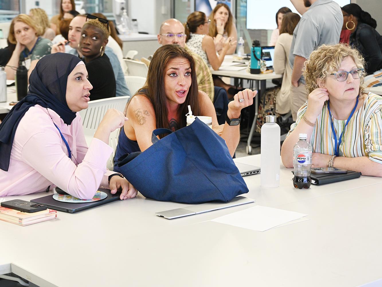 A group of students seated around a table holds a discussion during a small-group exercise.