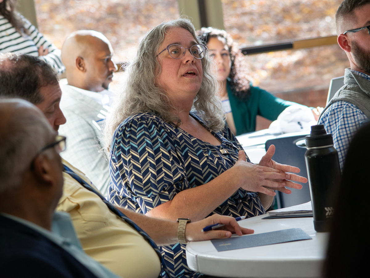 Individual speaking with several individuals seated around them