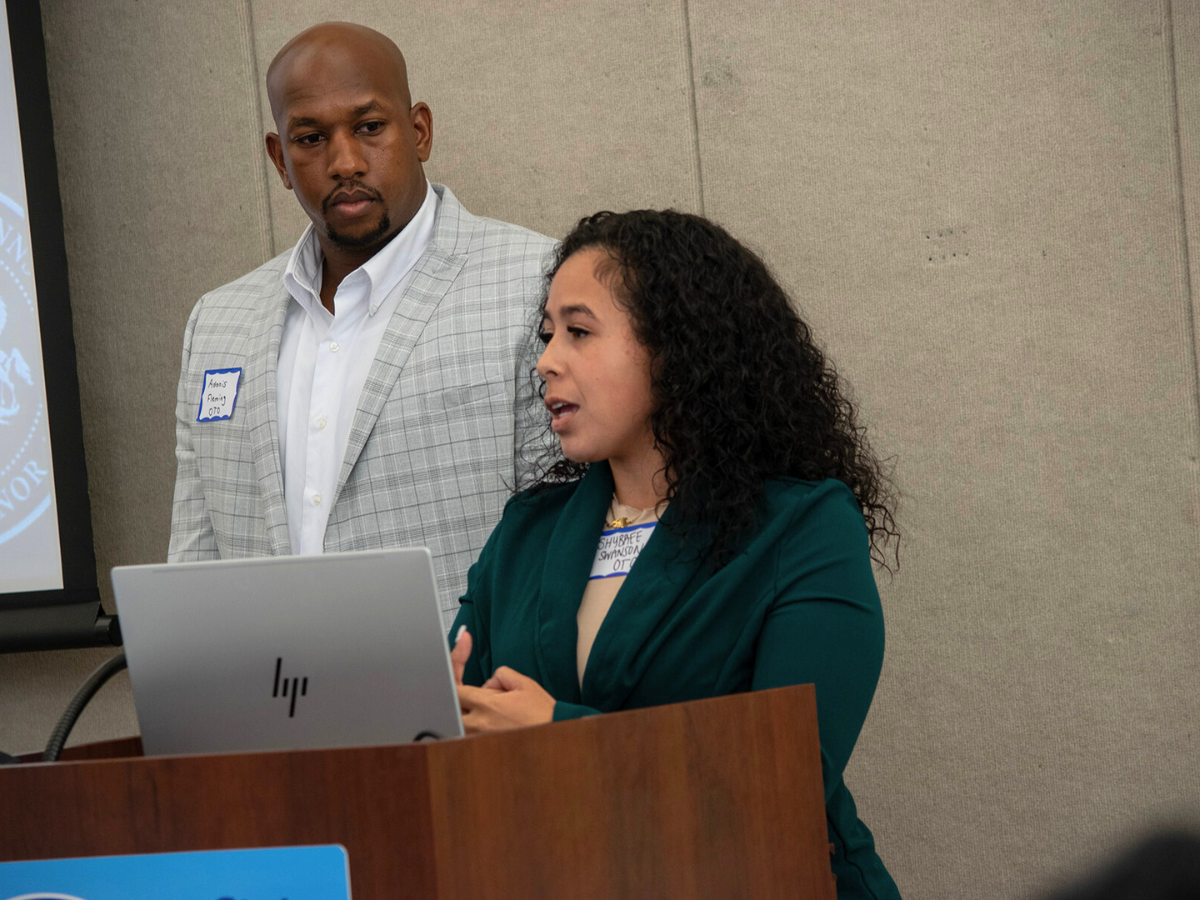 Two individuals stand behind podium presenting