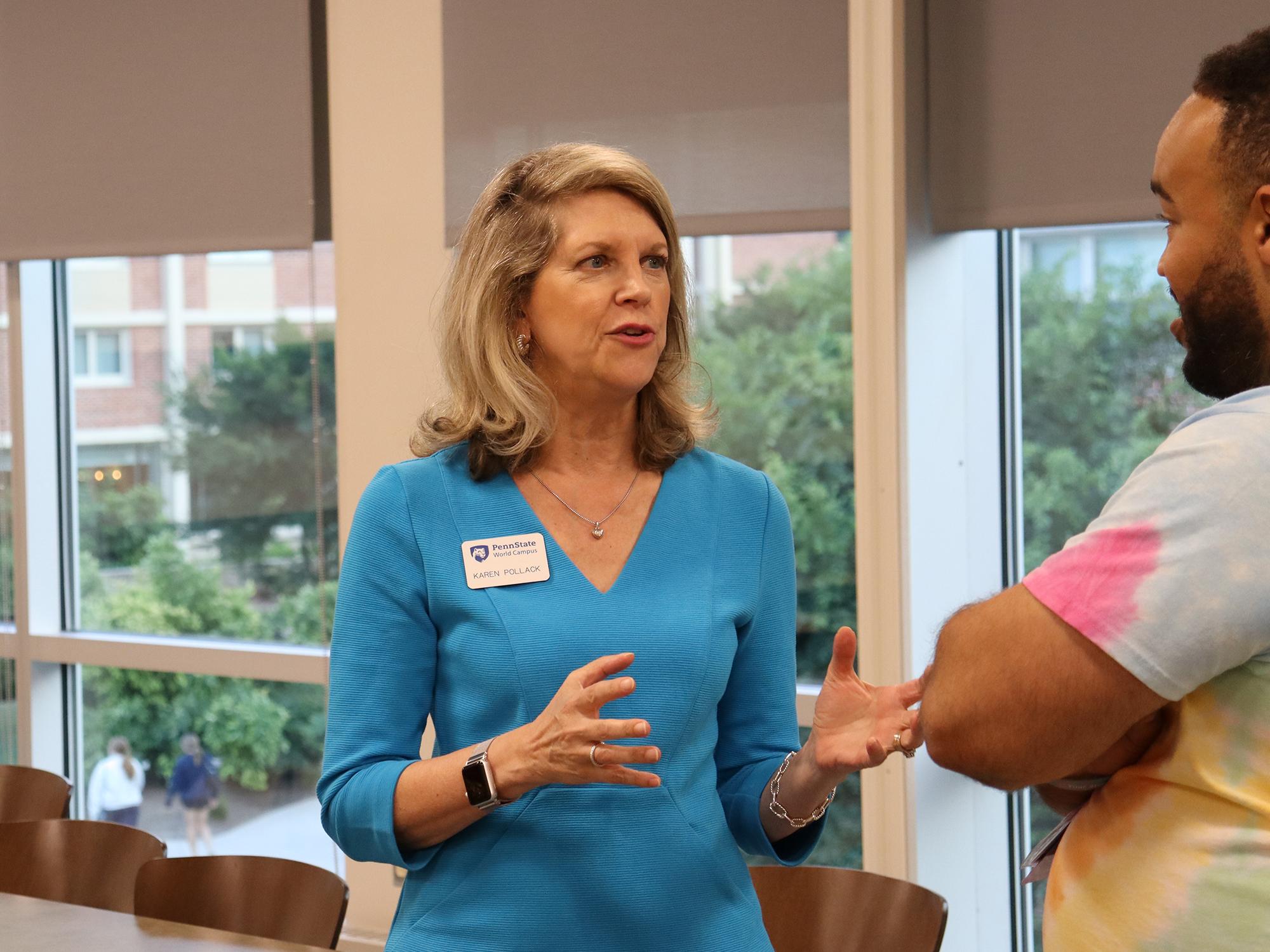 A woman in a blue dress talks to a man wearing a tie-dye shirt.