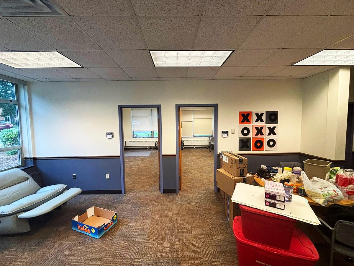 A wide shot of the Veterans Lounge in progress, with two doors visible and boxes and furniture spread about the room