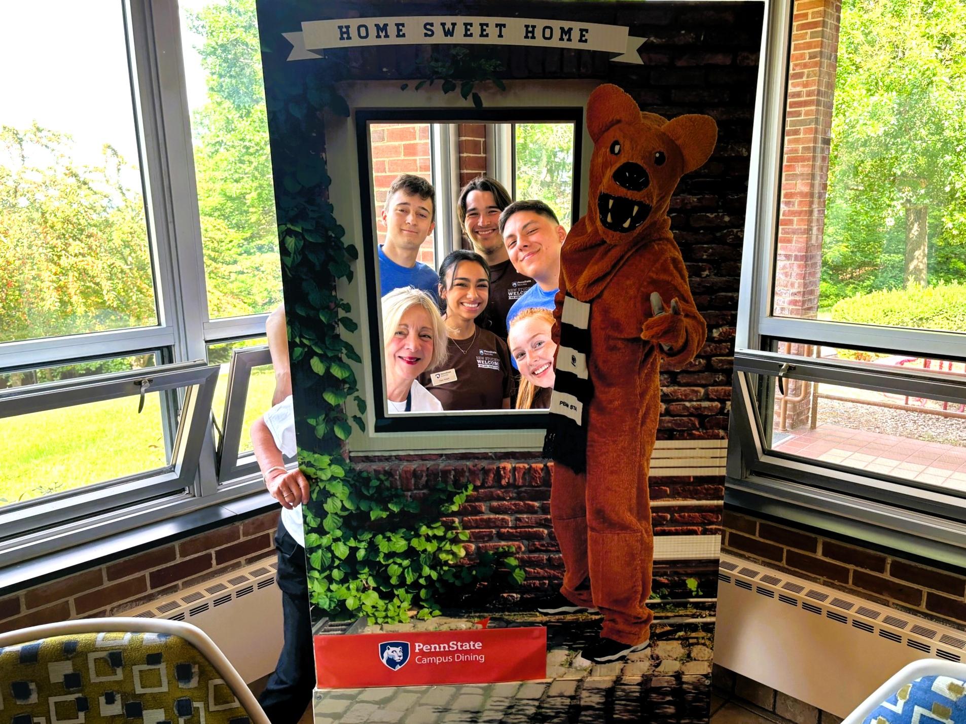 A group of people pose through a pop up photo frame