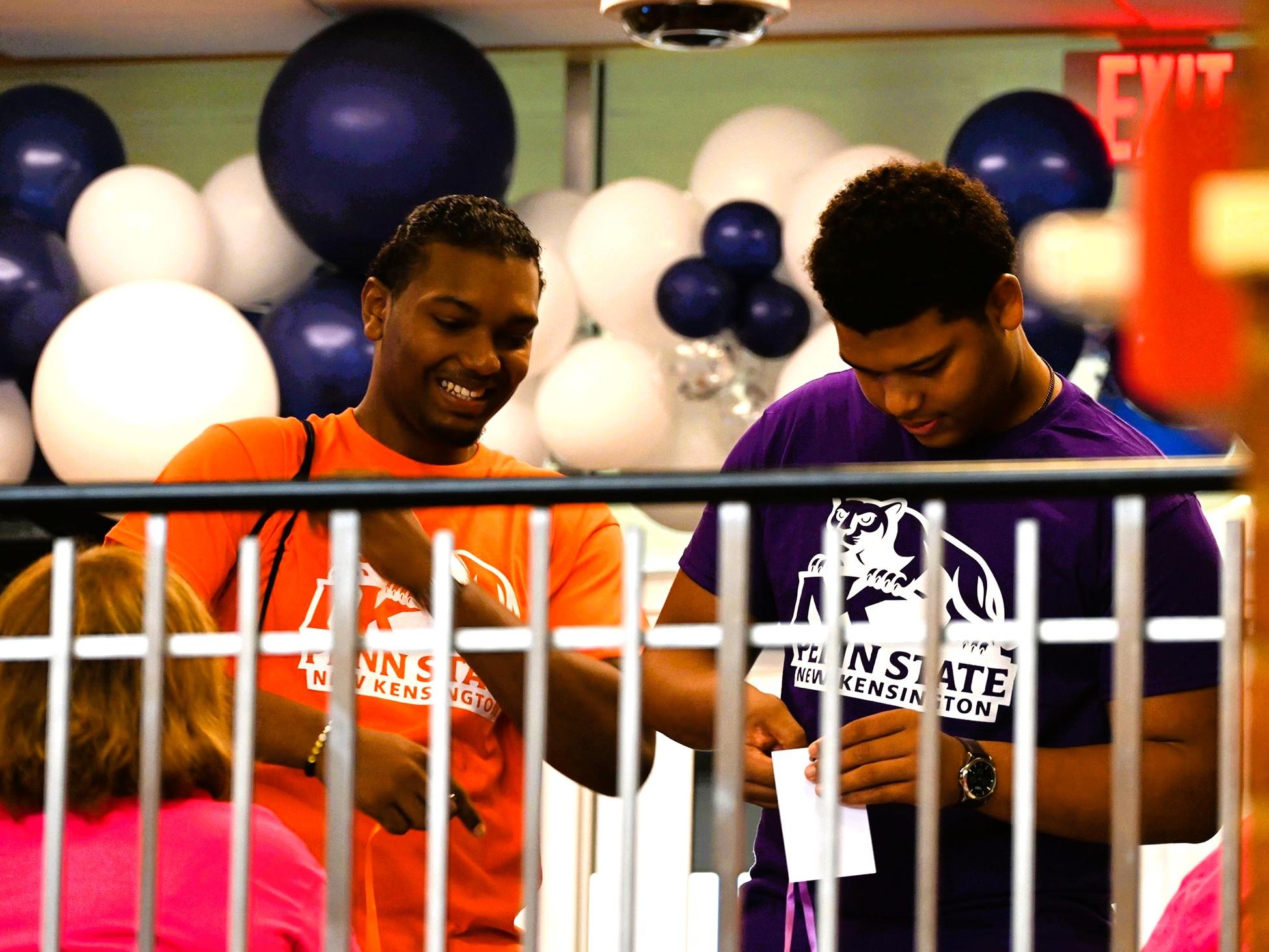 Two students wearing Penn State New Kensington t-shirts have fun at an event