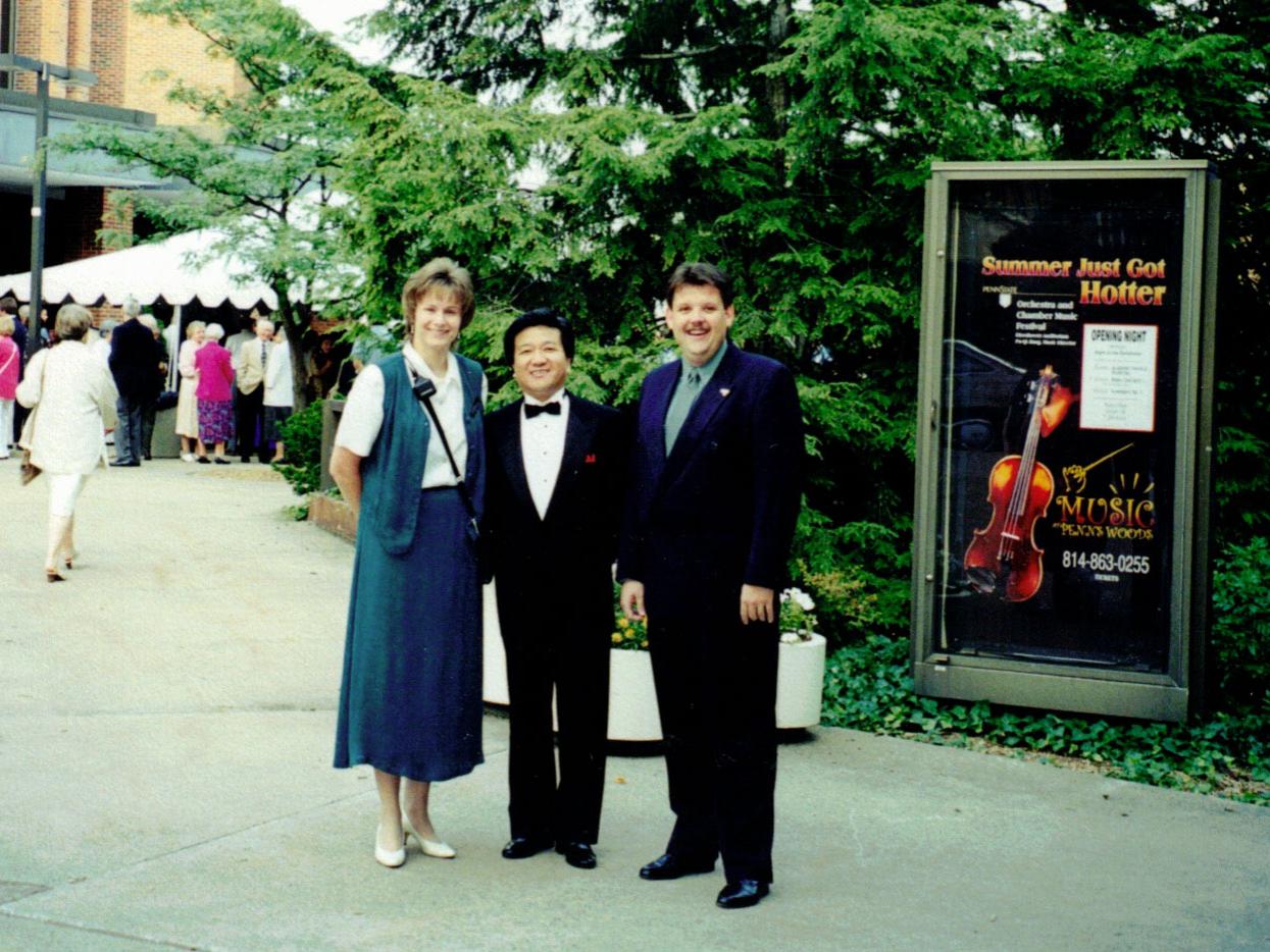 A woman and two men stand in front of Eisenhower Auditorium.