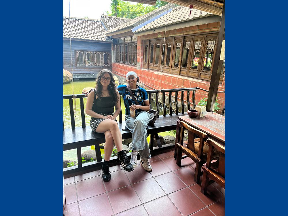 Two people sitting on a bench outside on a porch.