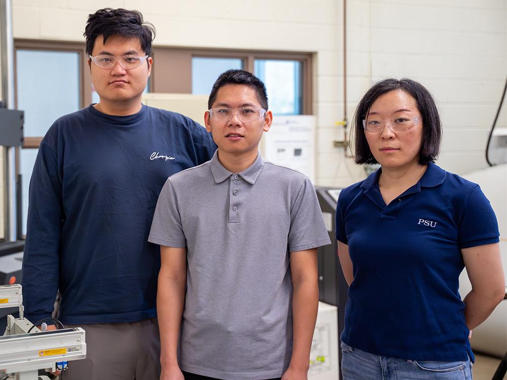 Three researchers standing in a manufacturing lab smiling for a picture together.