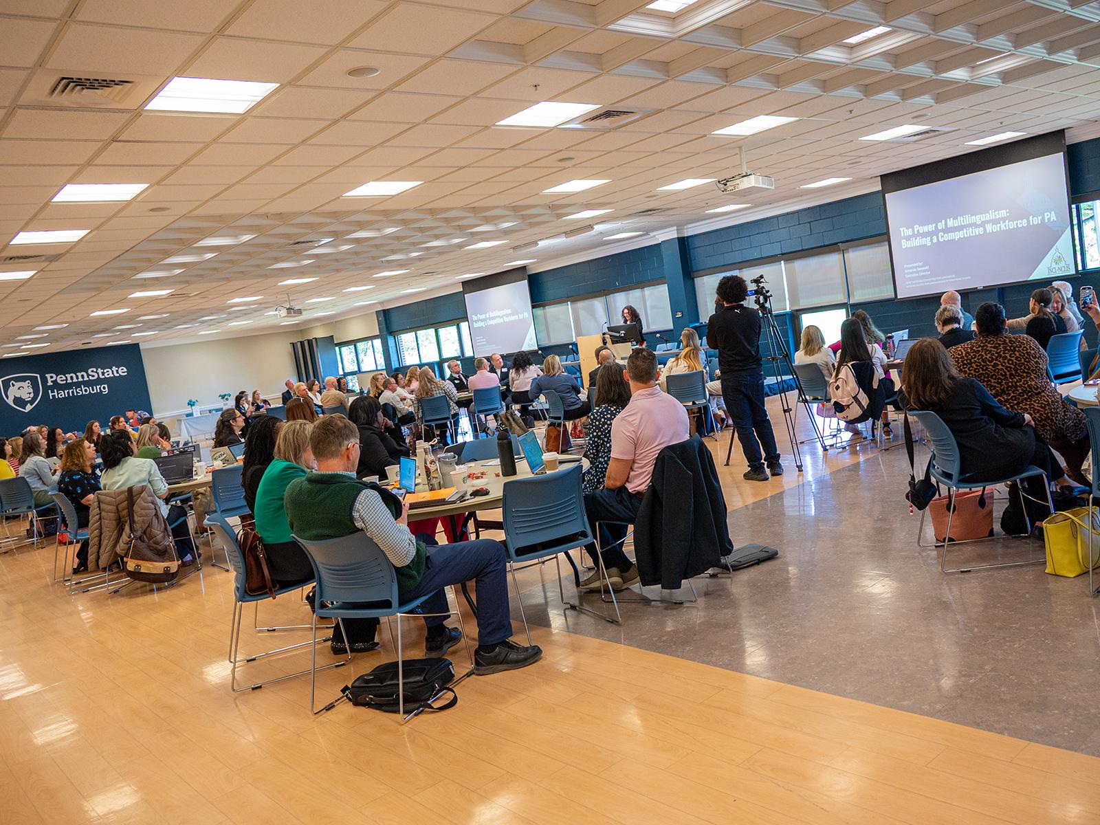 People sit at tables and listen to a speaker