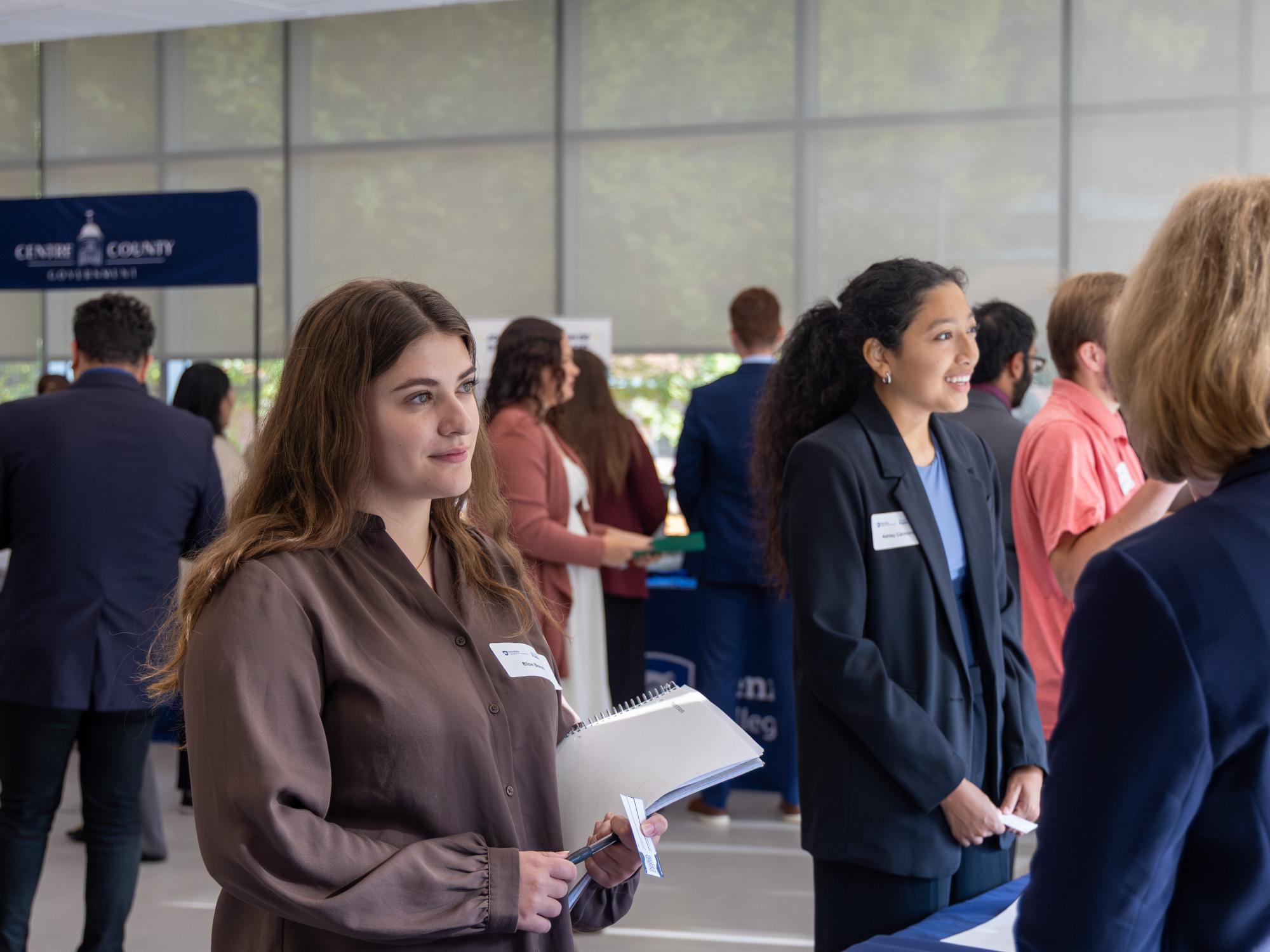 Two students speak with representatives in the Welch Building.