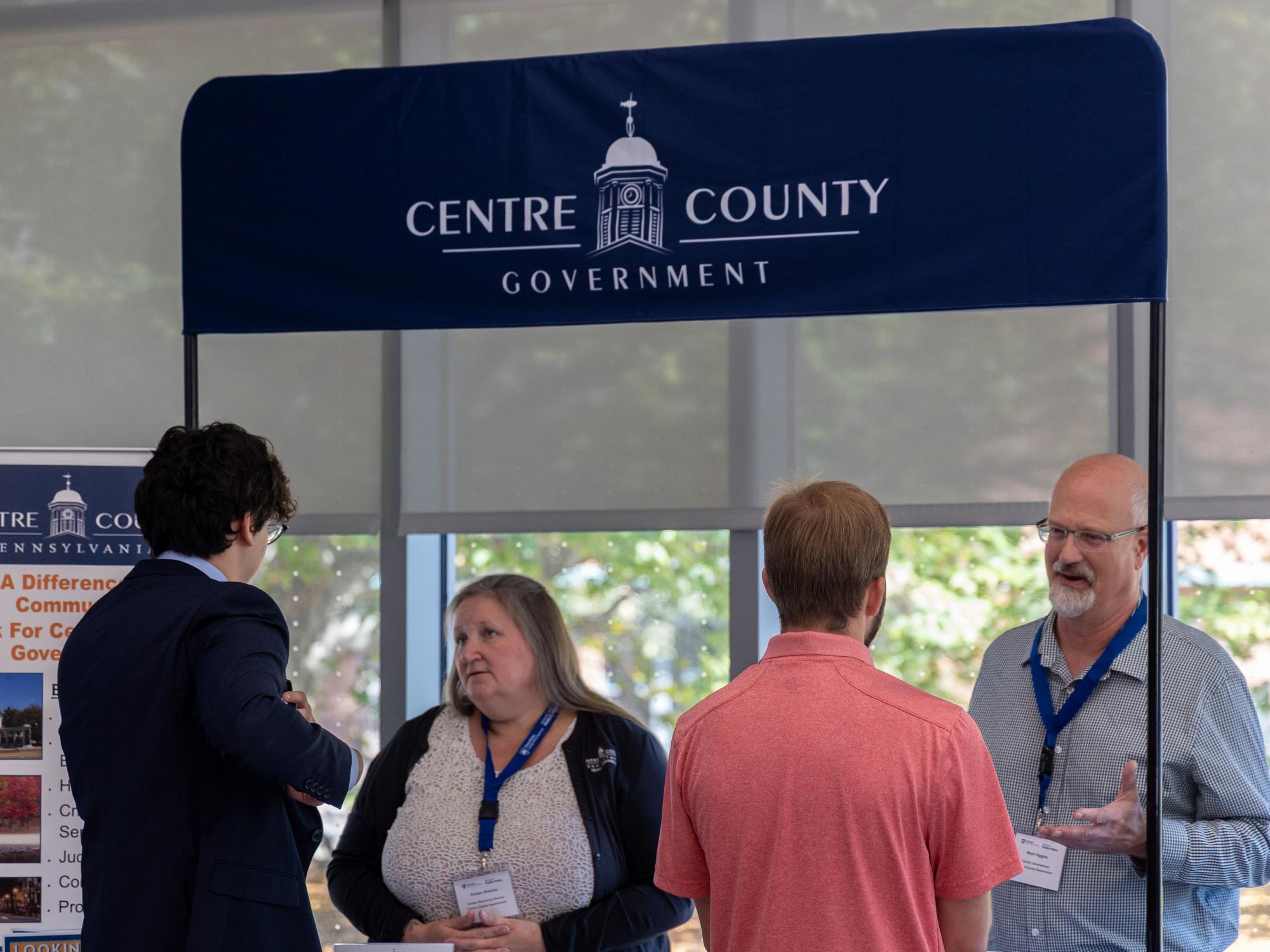 Human Resources Director Kristen Simkins and County Commissioner Mark Higgins speak with two students at the Local Government Career Fair.