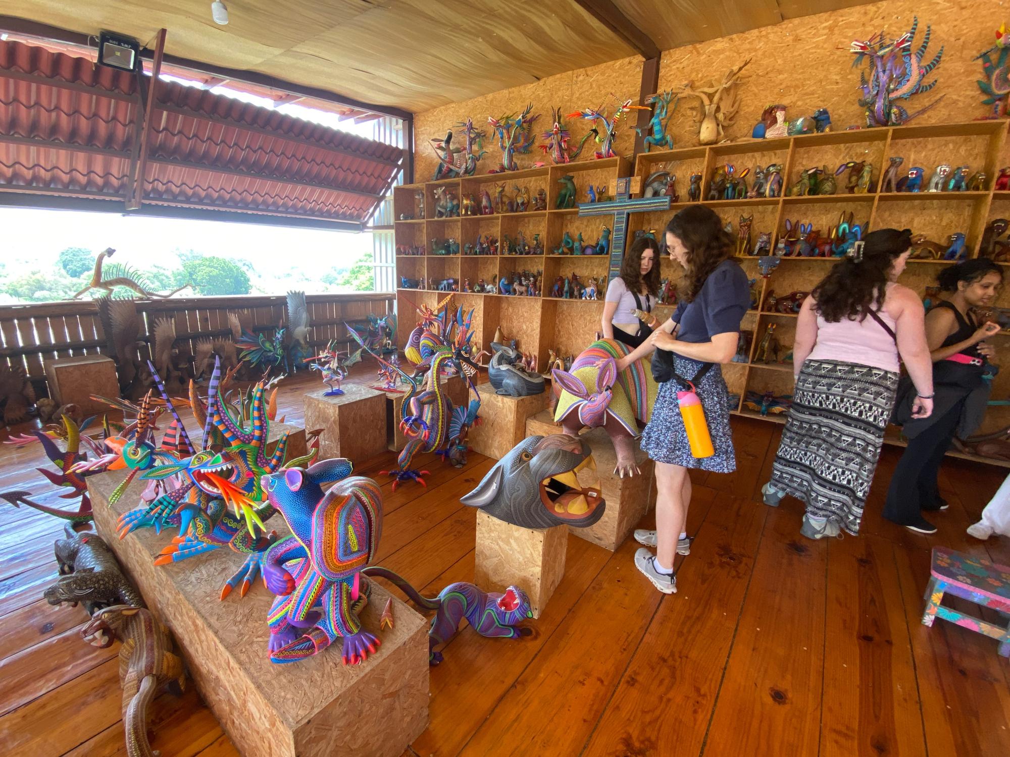 Students look at vibrantly colored wooden figures called alebrijes. 