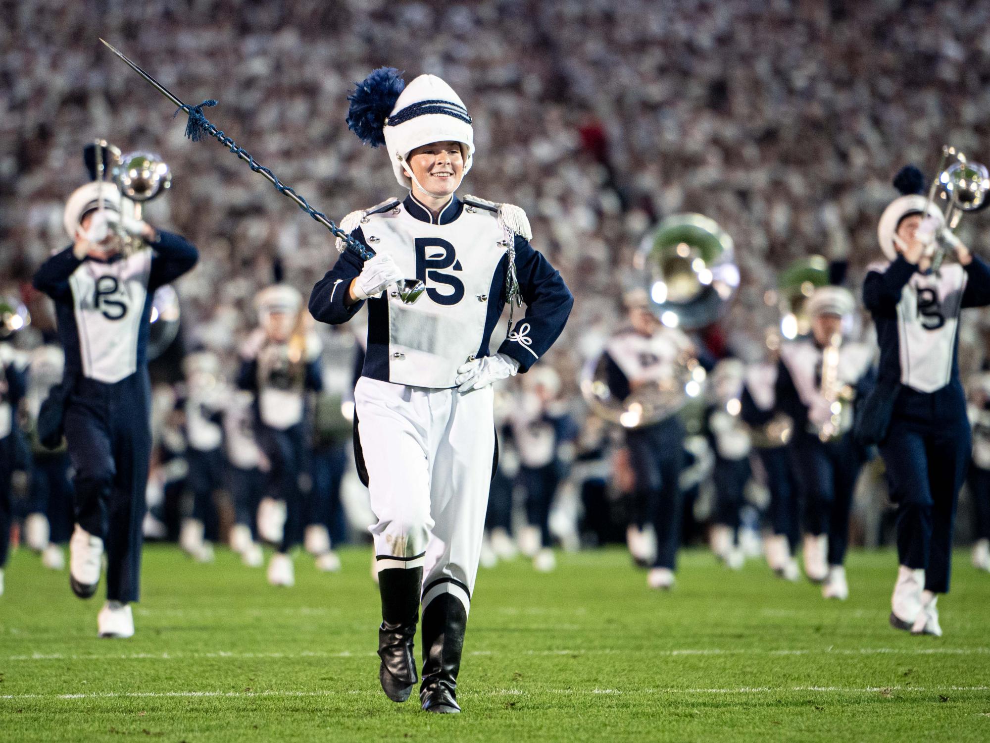 A drum major leading the band on a football field