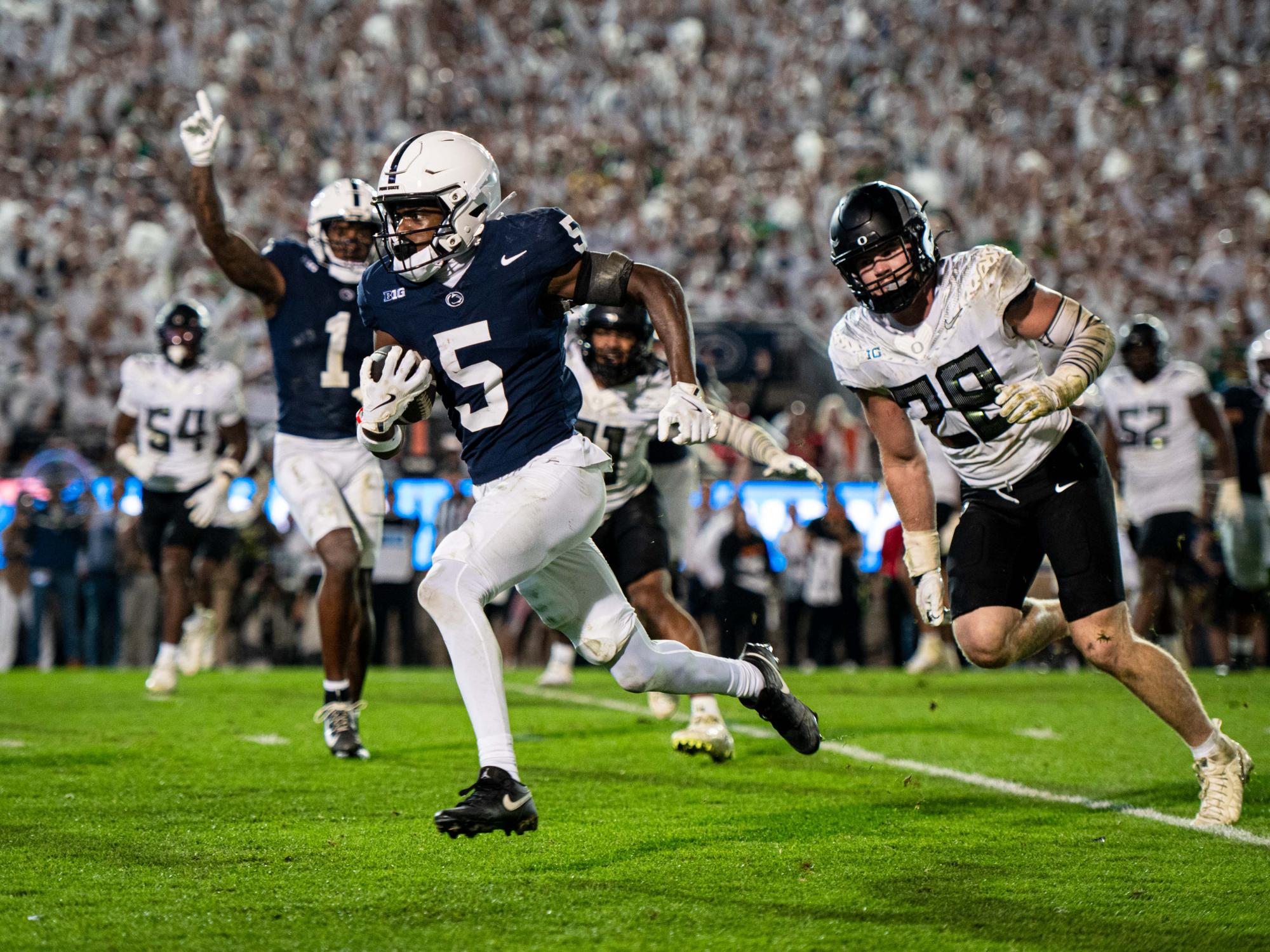 A football player holding a football and running on a field 