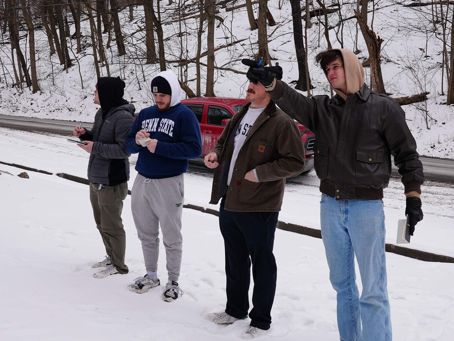Students standing in the snow looking at something outside of the photographed area..
