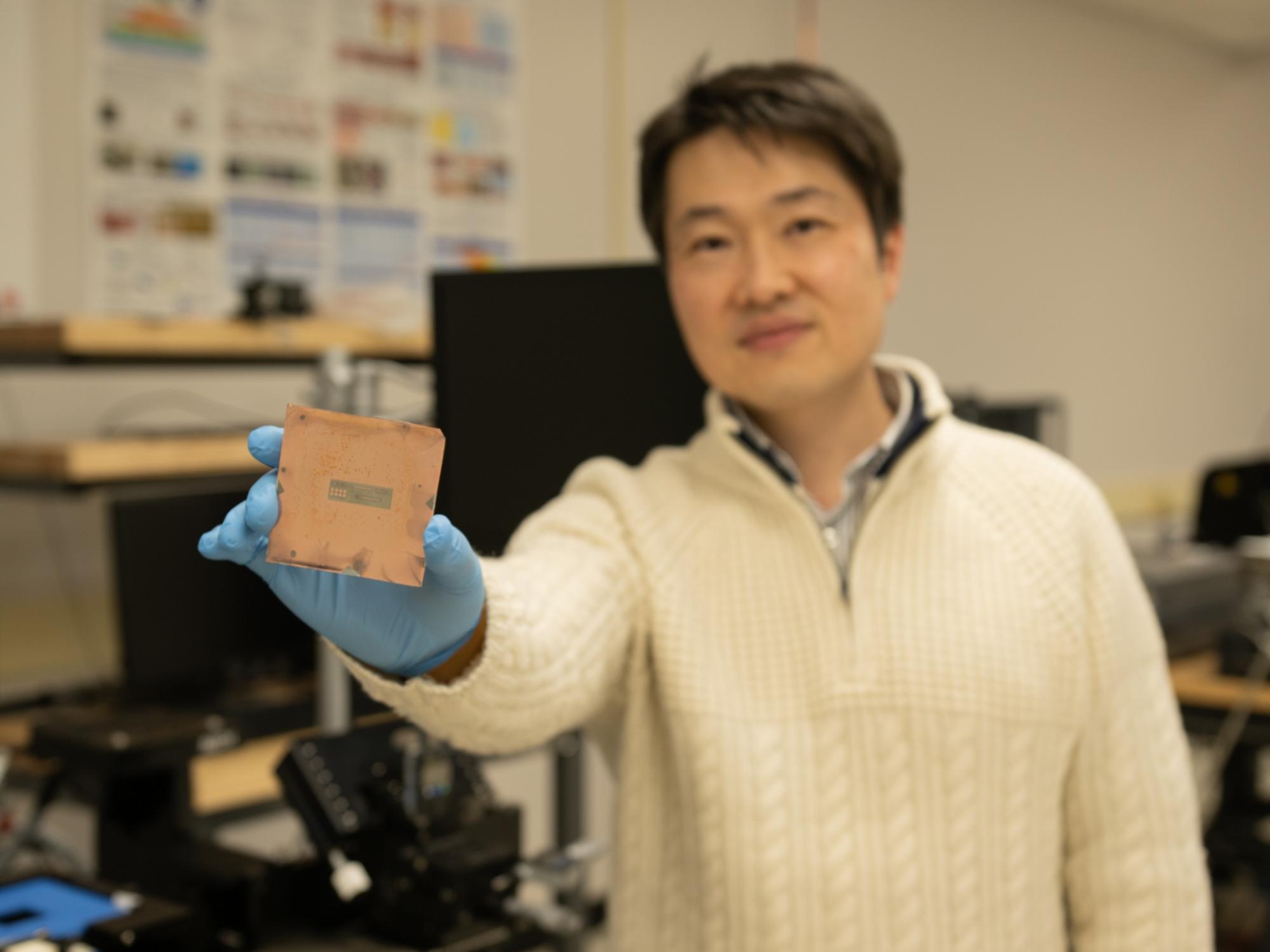 A person in a lab holds a square object