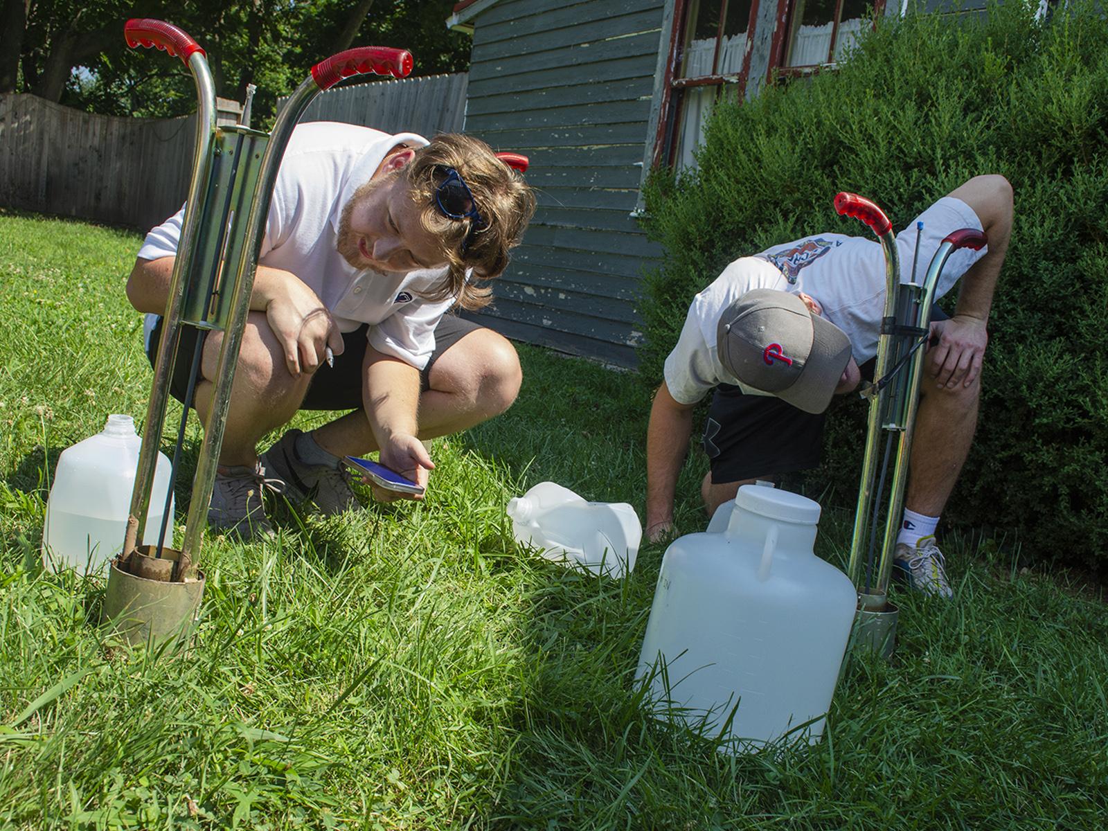 Two men conducting infiltration tests on the soil