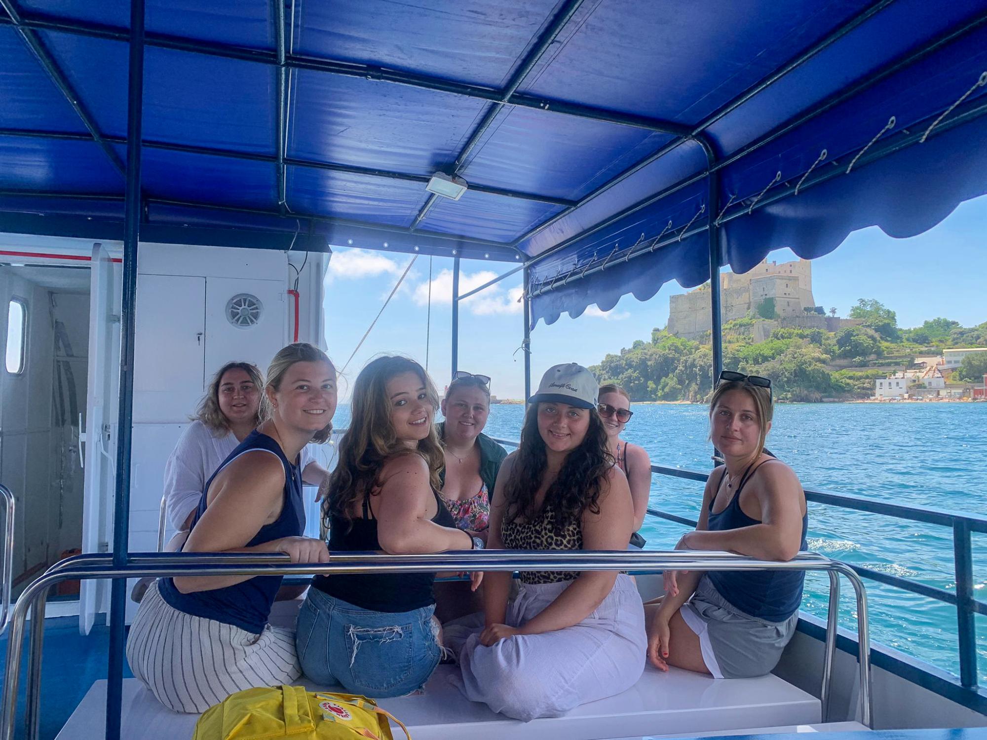 Seven Penn State students sit on a boat while touring the Amalfi Coast.