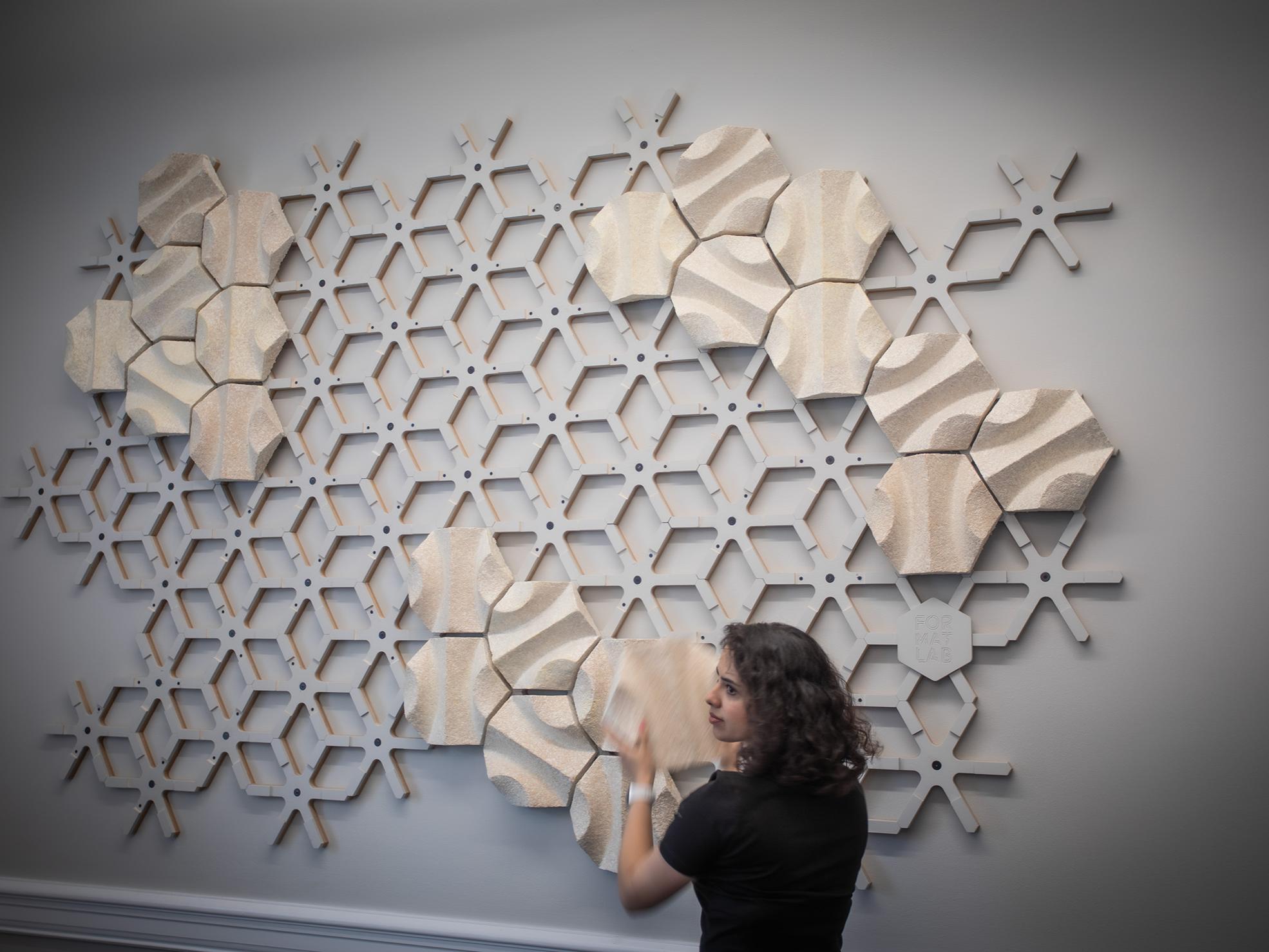 An individual installing sound-absorbing components to the acoustic wall.
