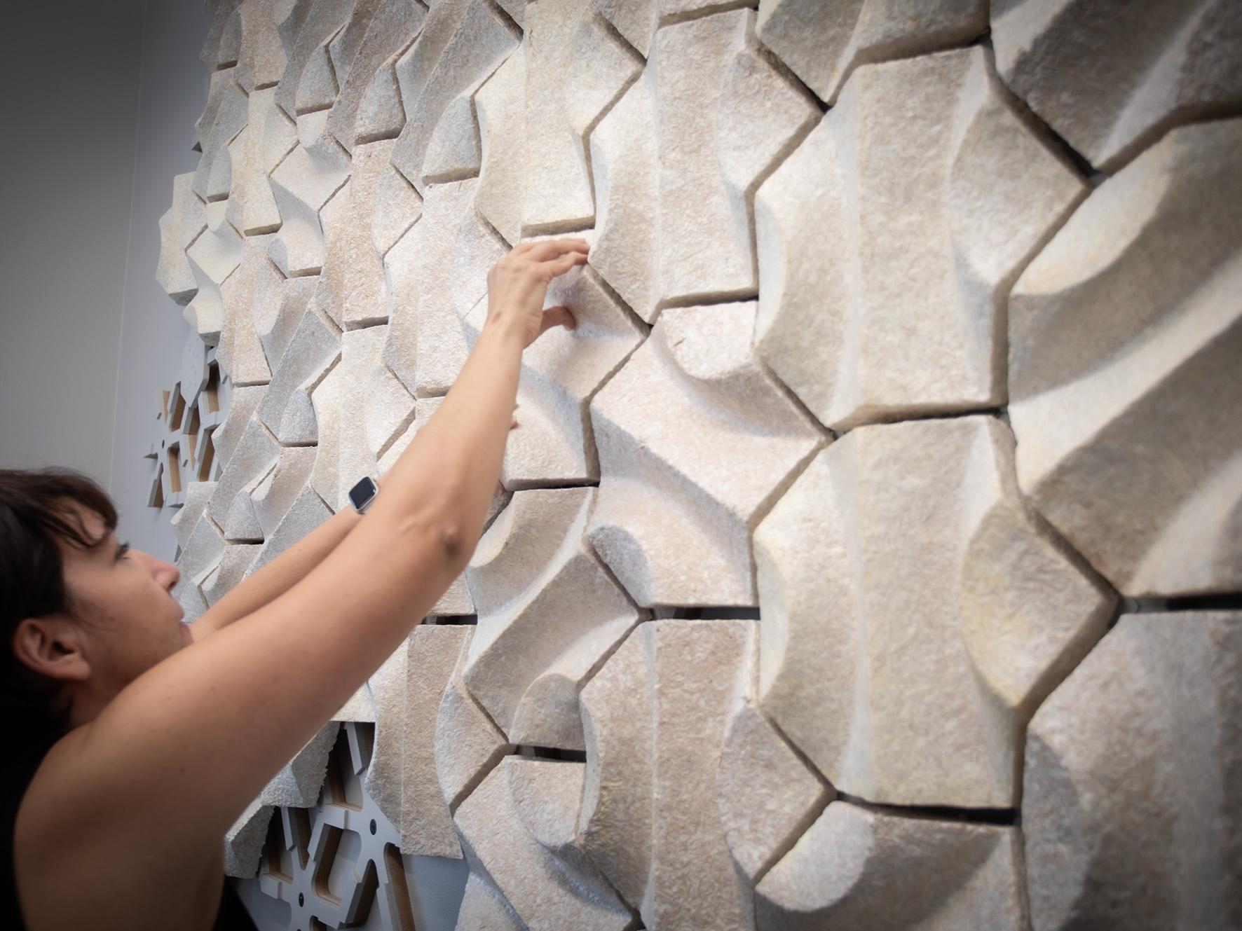 An individual applies components to the framework of the acoustic wall. 