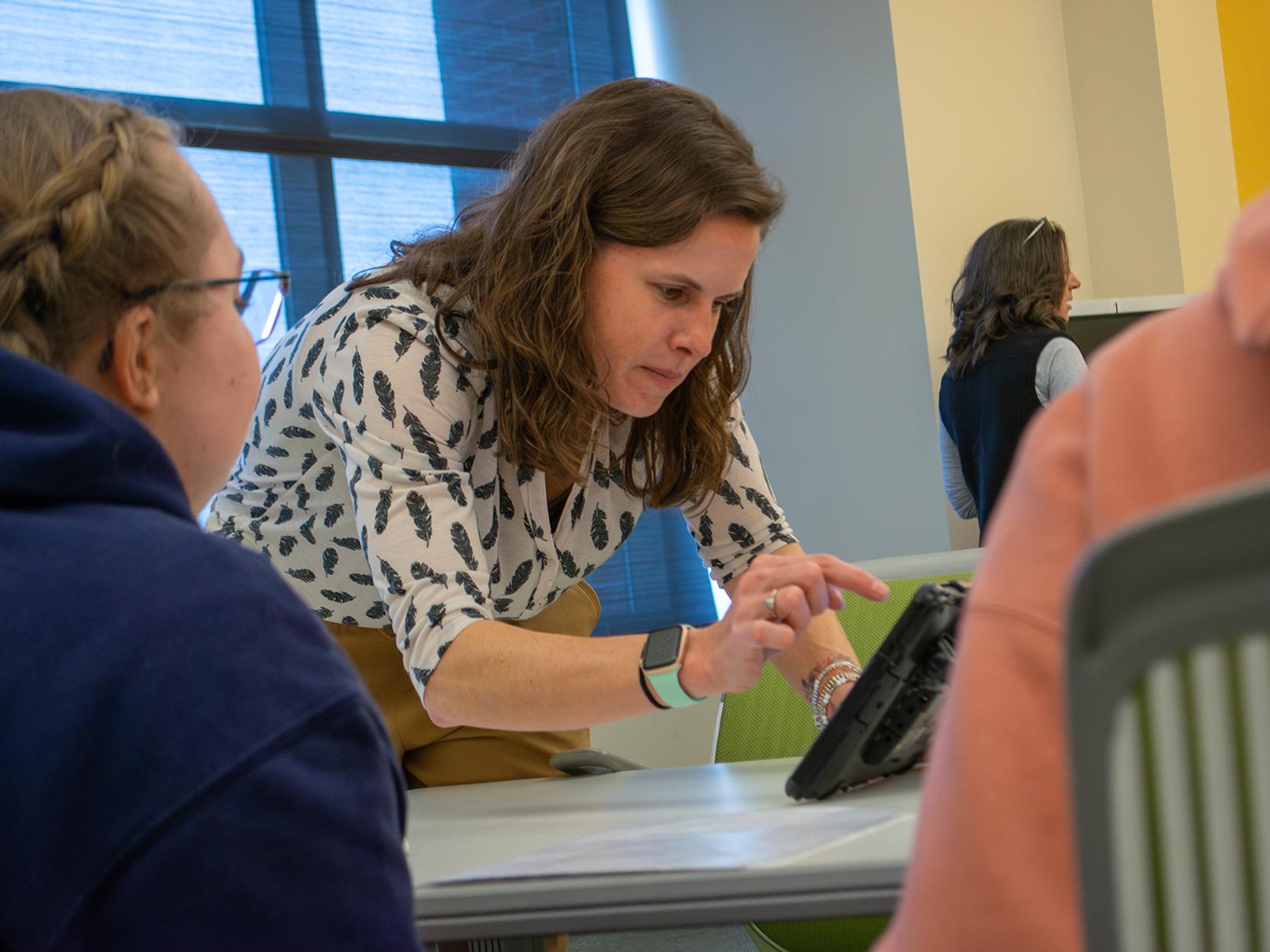 A professor types on the screen of an alternative and augmentative communication device during her class