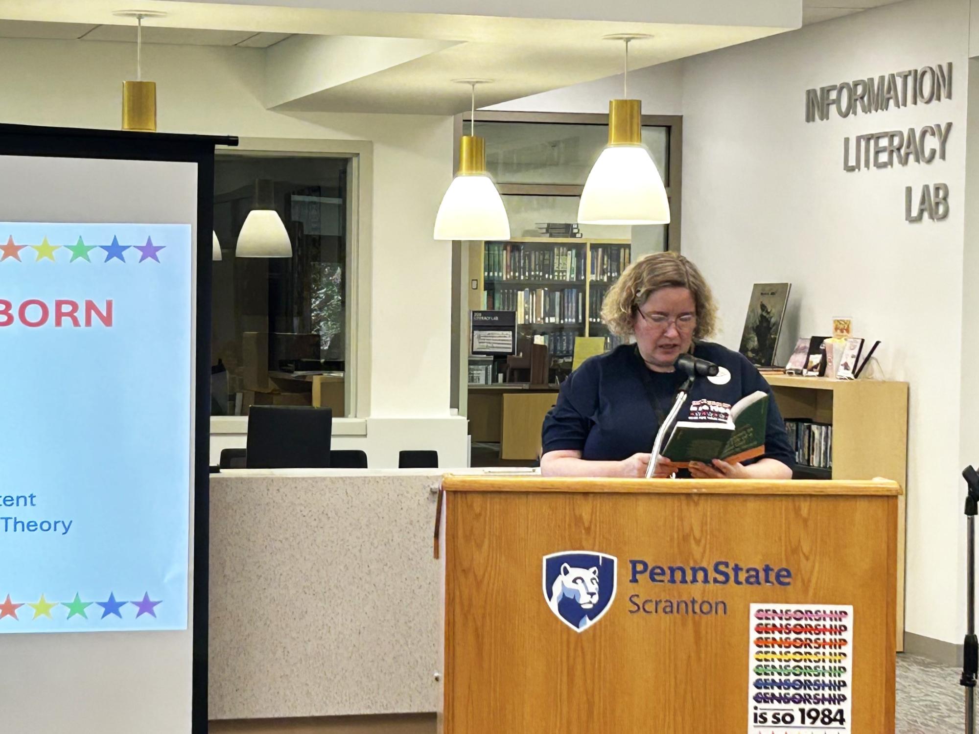 woman reading from a book standing at podium