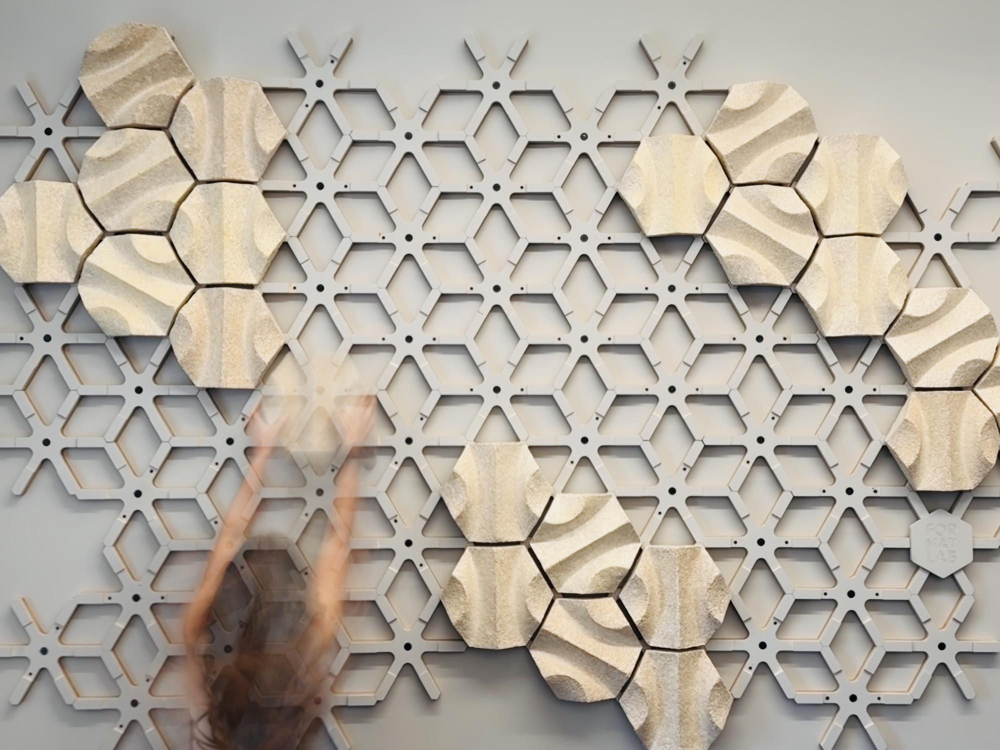 An individual adds mycelium components to an acoustic wall installation.