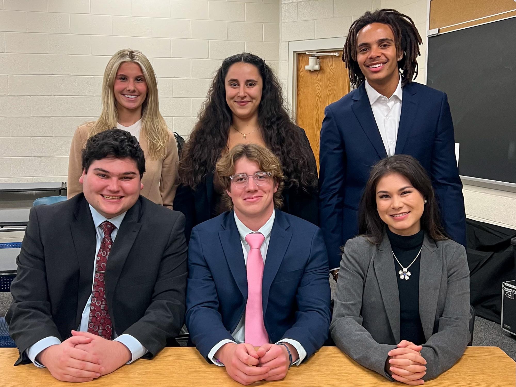 Olivia Cimbora, seated at the right, poses with five other members of the Penn State Mock Trial team.