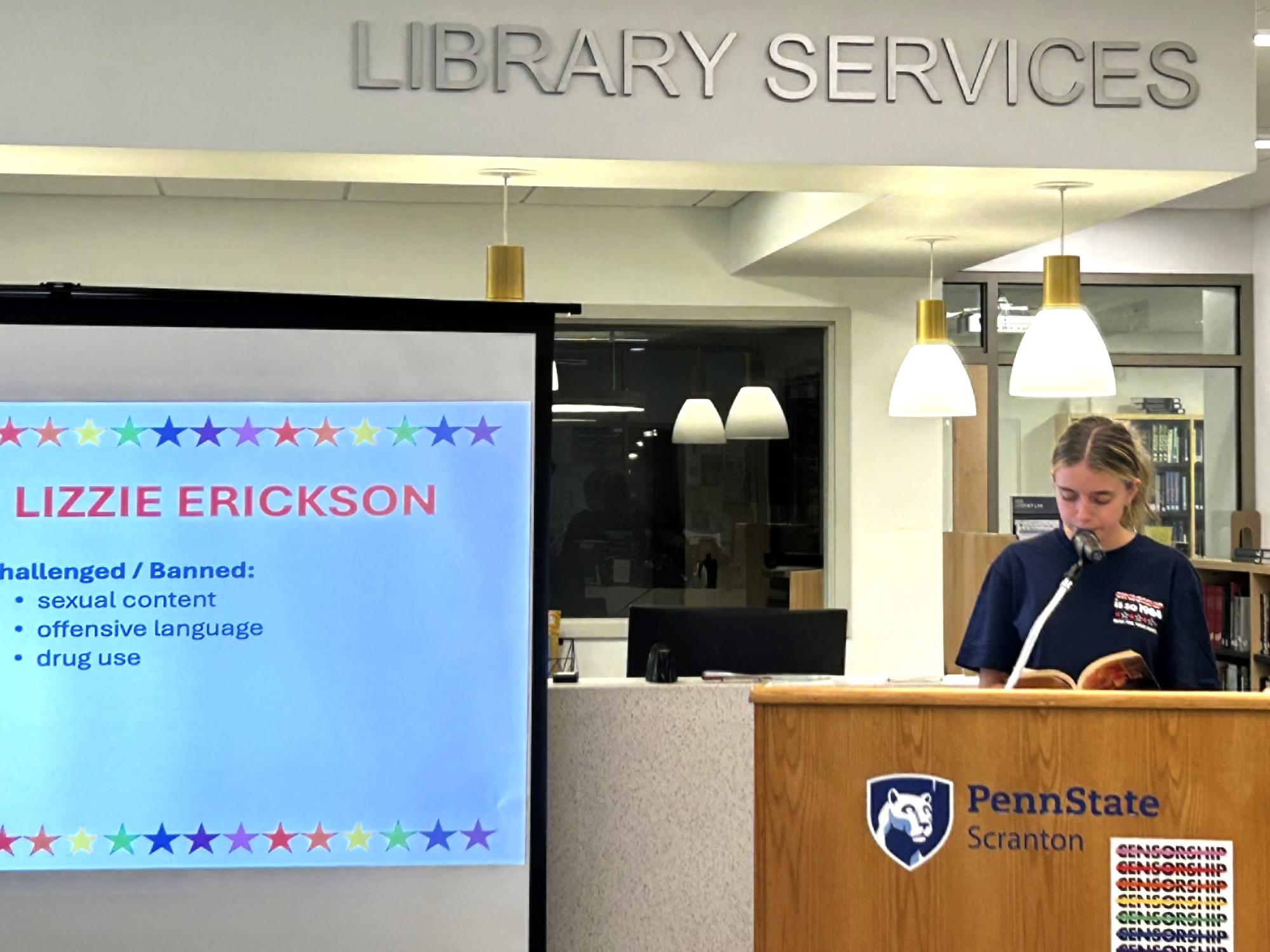 female student reads from her book at podium during event