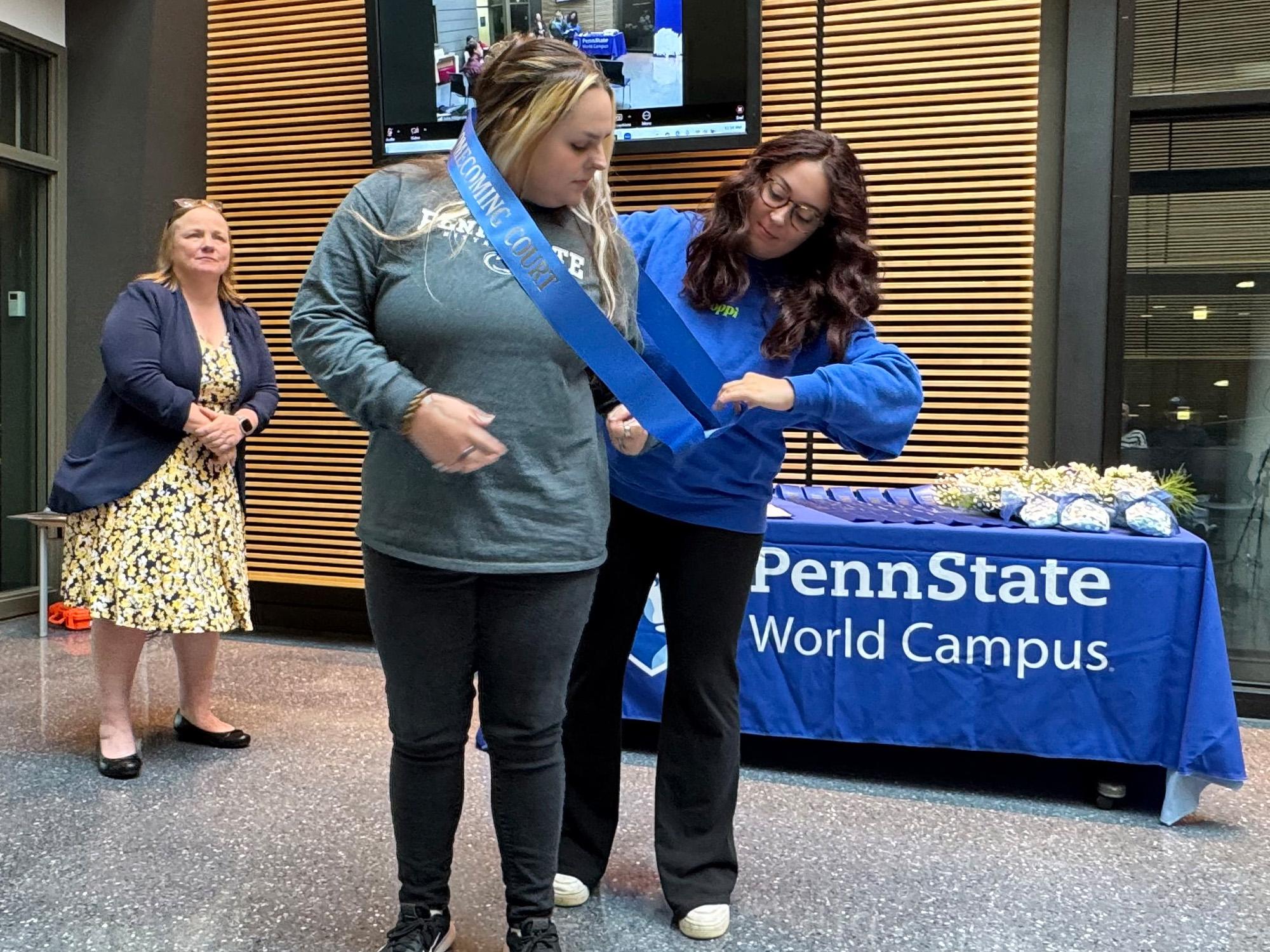 a woman puts a sash on another woman