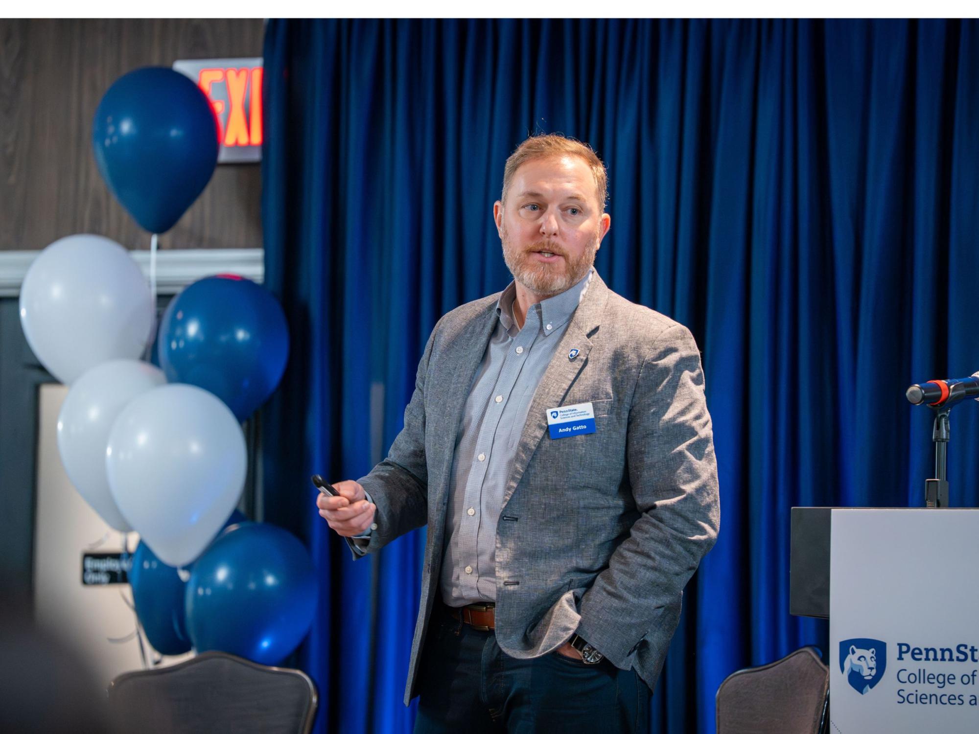 person in casual business attire stands next to blue and white balloons